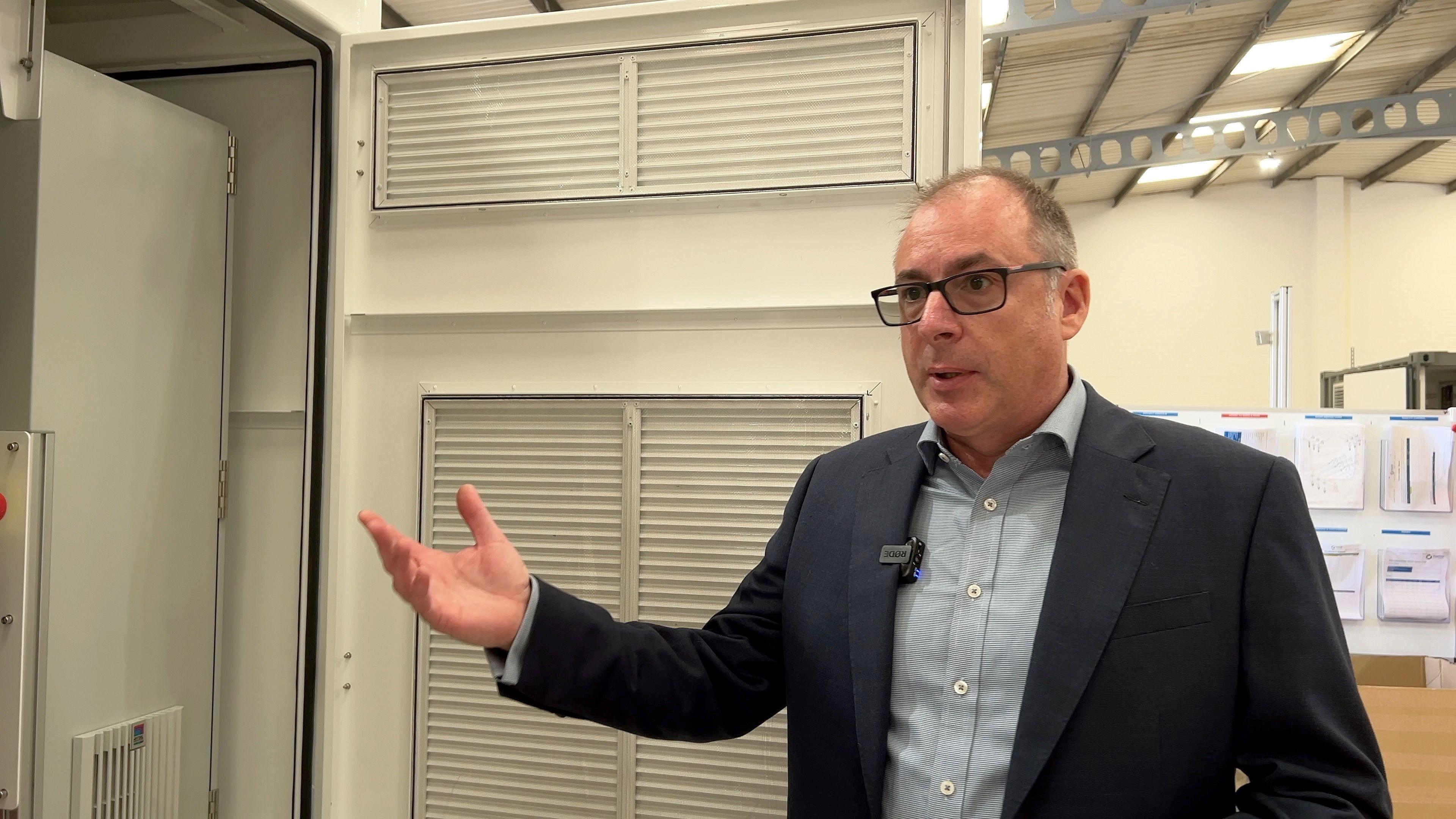 Dr Lee Juby, CEO of Fuel Cell Systems, stads beside the open door leading into one of the firm's trial hydrogen dispensers.