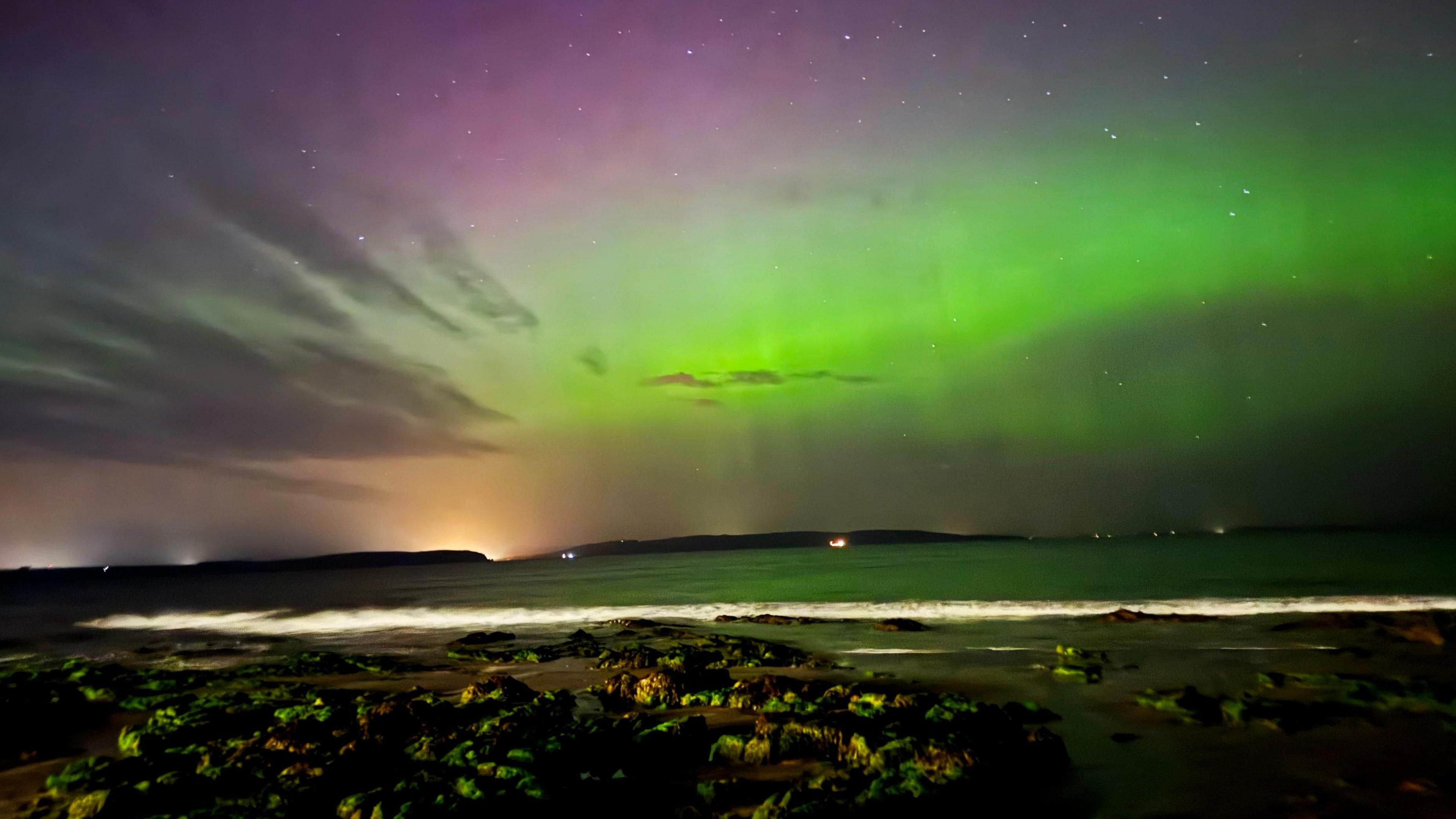 The sky glowing green and pink above a beach Nairn in the Highlands