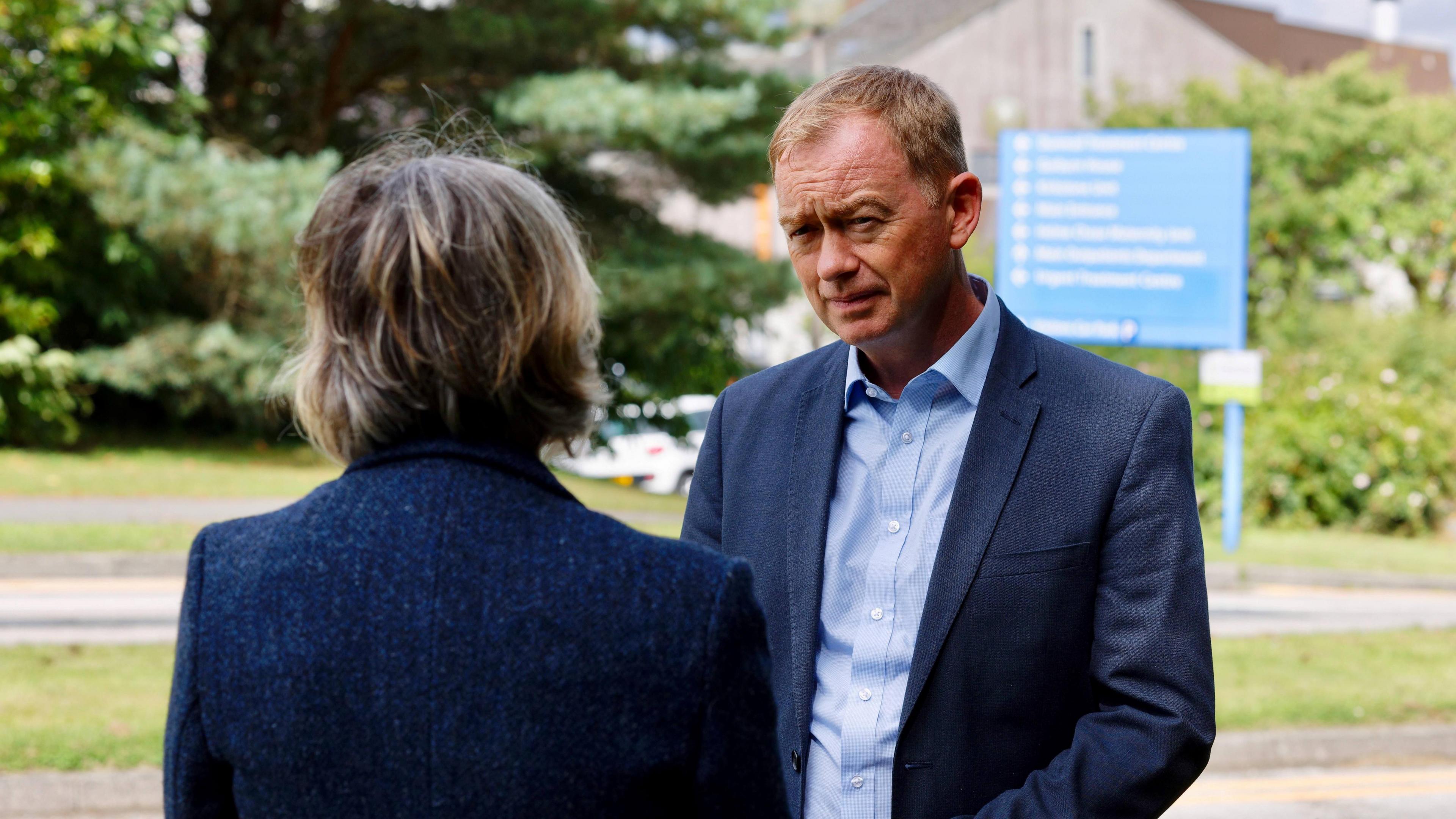 Tim Farron talking to a woman outside Westmorland General Hospital; the woman has her back to the camera.