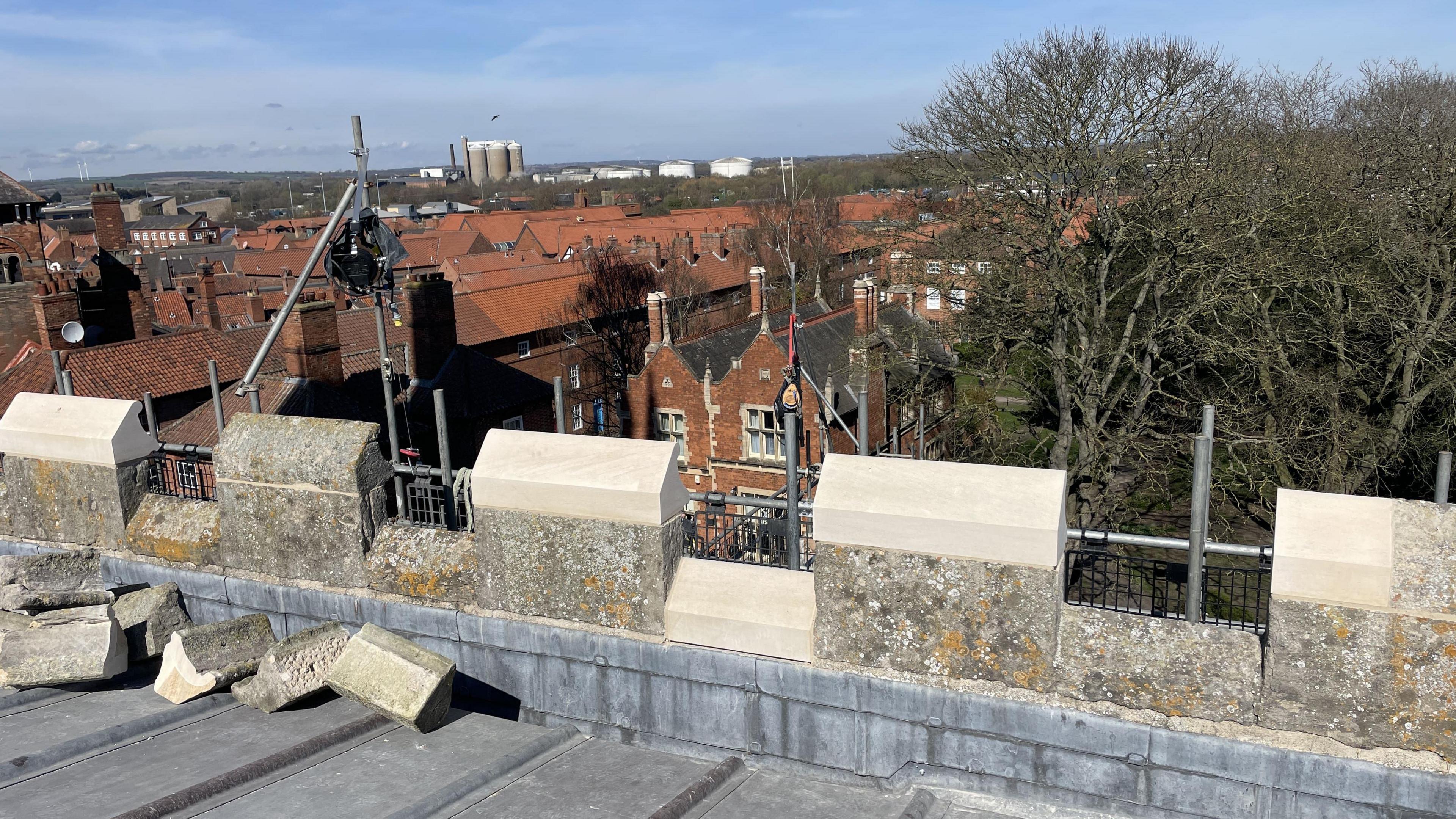 a view of house rooftops from the top of a church that is surrounded by scaffolding.