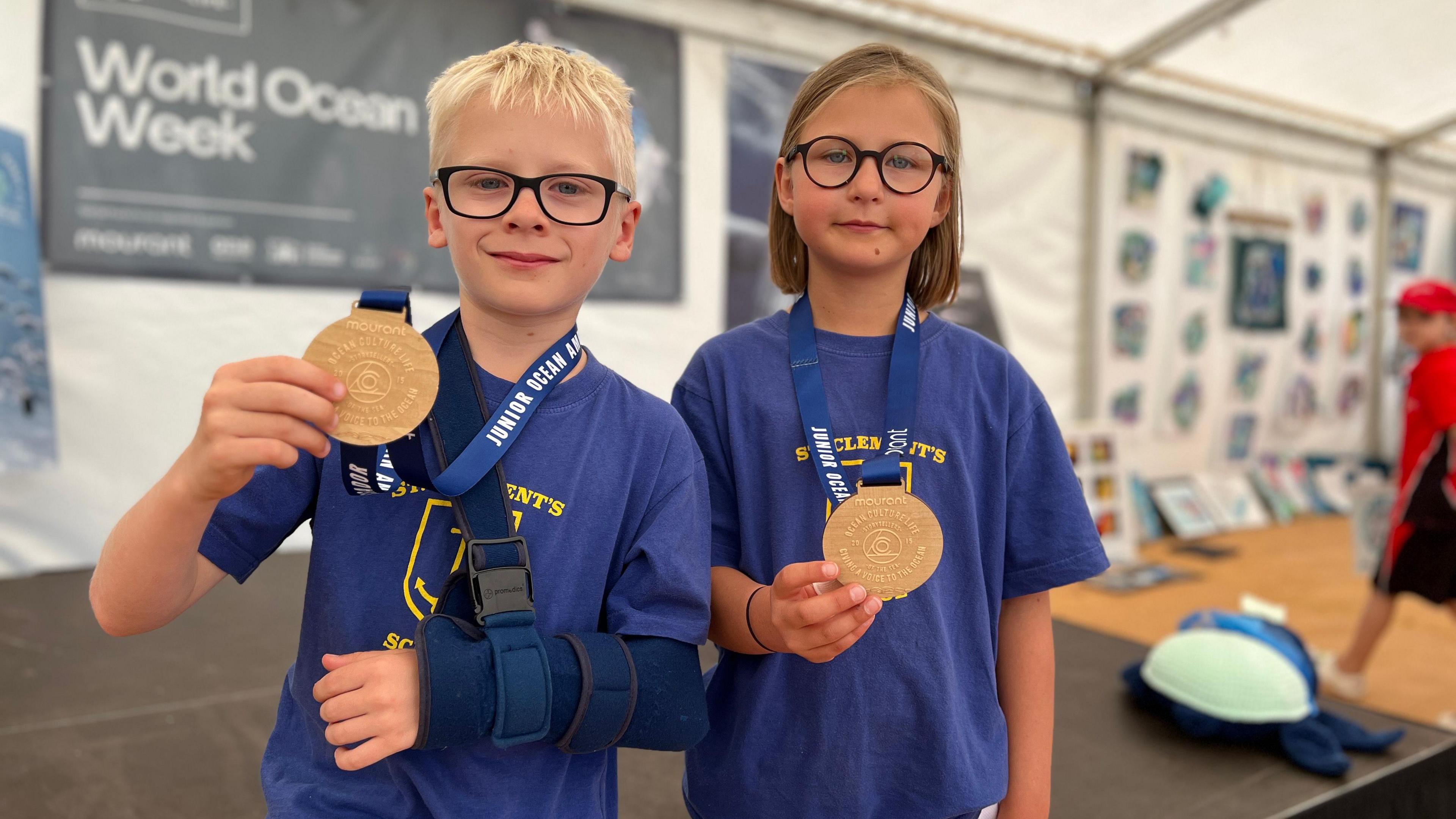 St Clement's School students look at the camera holding medals which say they are junior ocean ambassadors