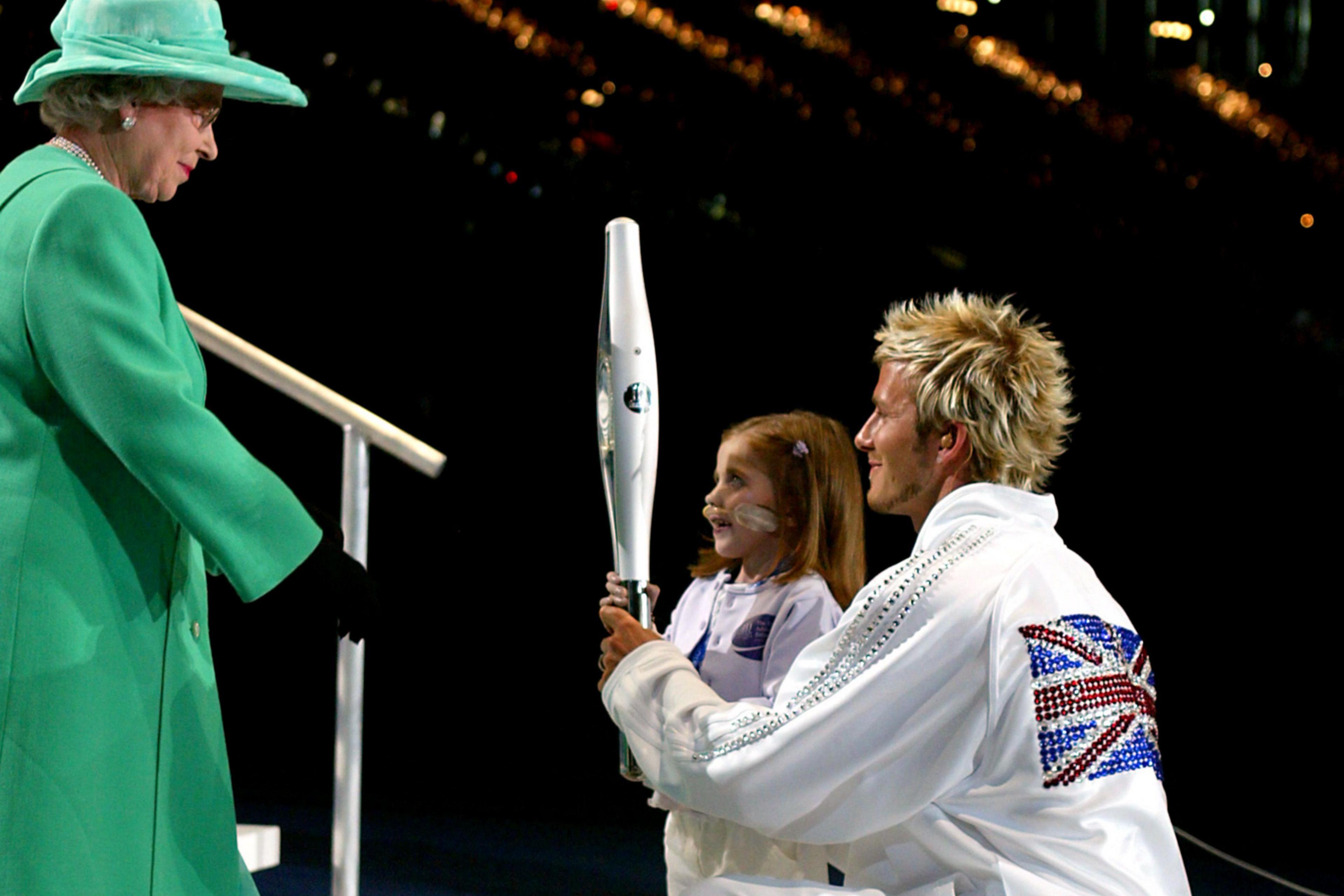 David Beckham and Kirsty Howard hand the Jubilee Baton to Queen Elizabeth II during the Manchester Commonwealth Games opening ceremony in 2002
