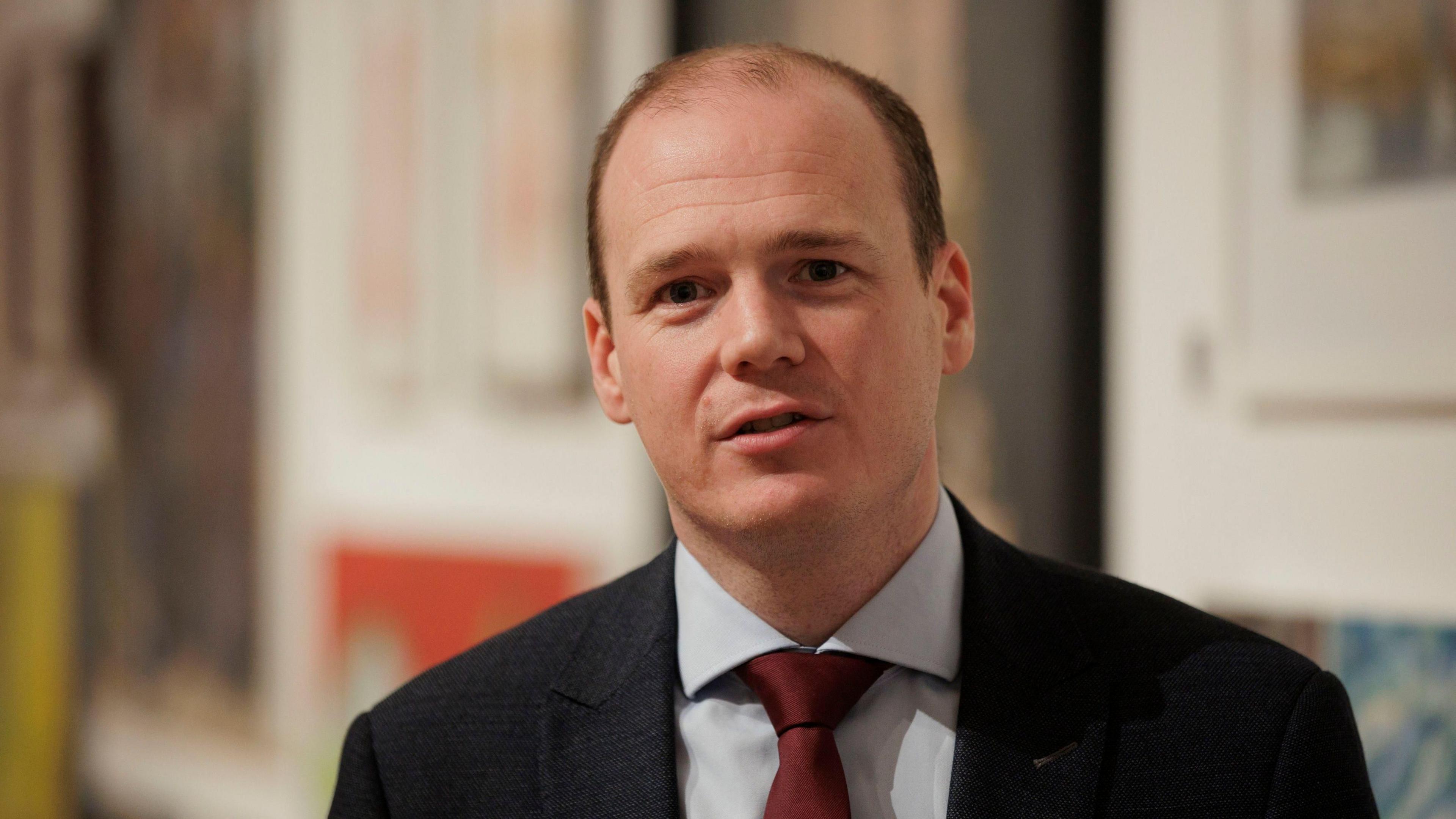 Gordon Lyons in a suit jacket and red tie