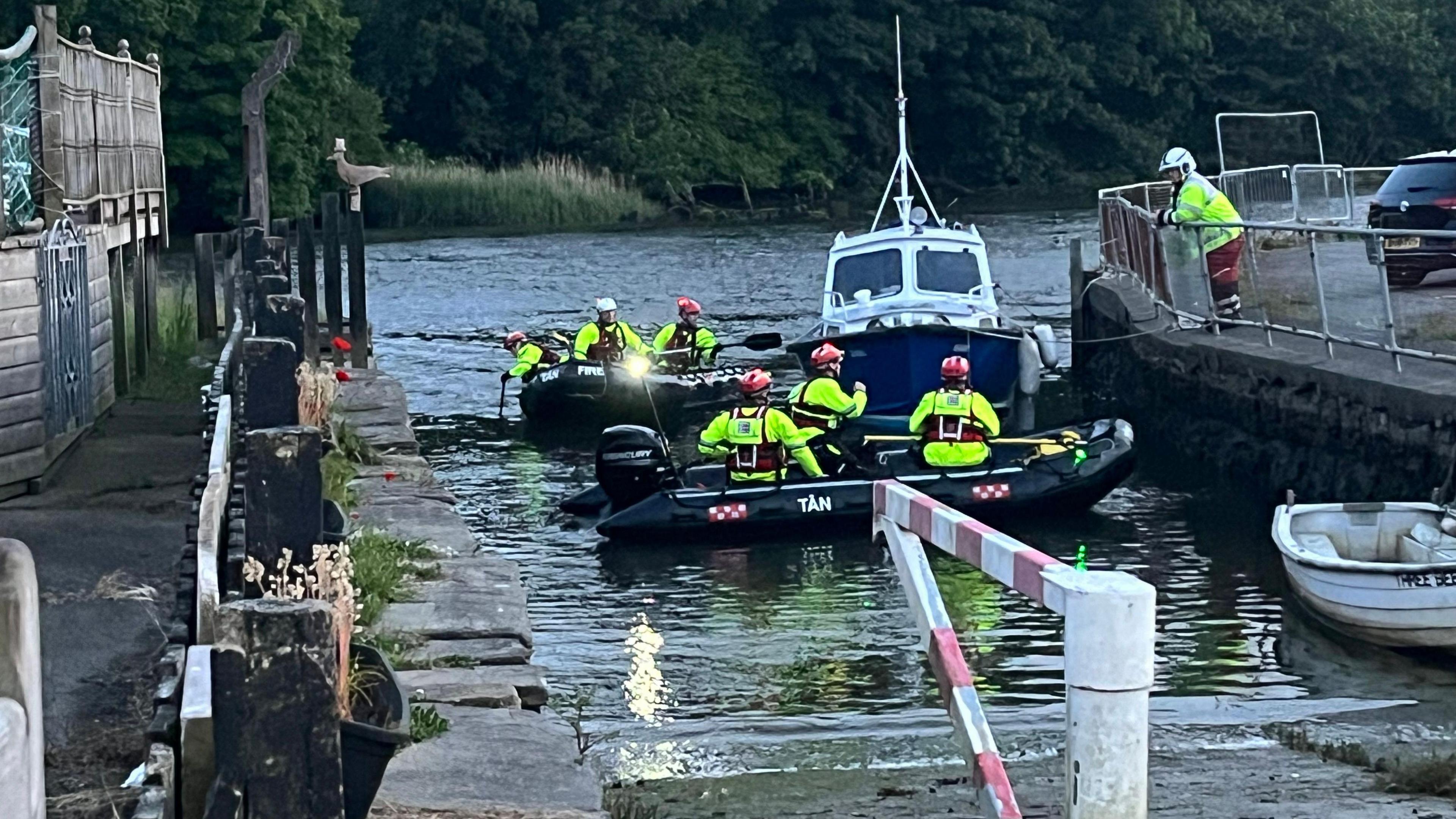 RNLI crew in neon search gear in inflatable boats at a pier