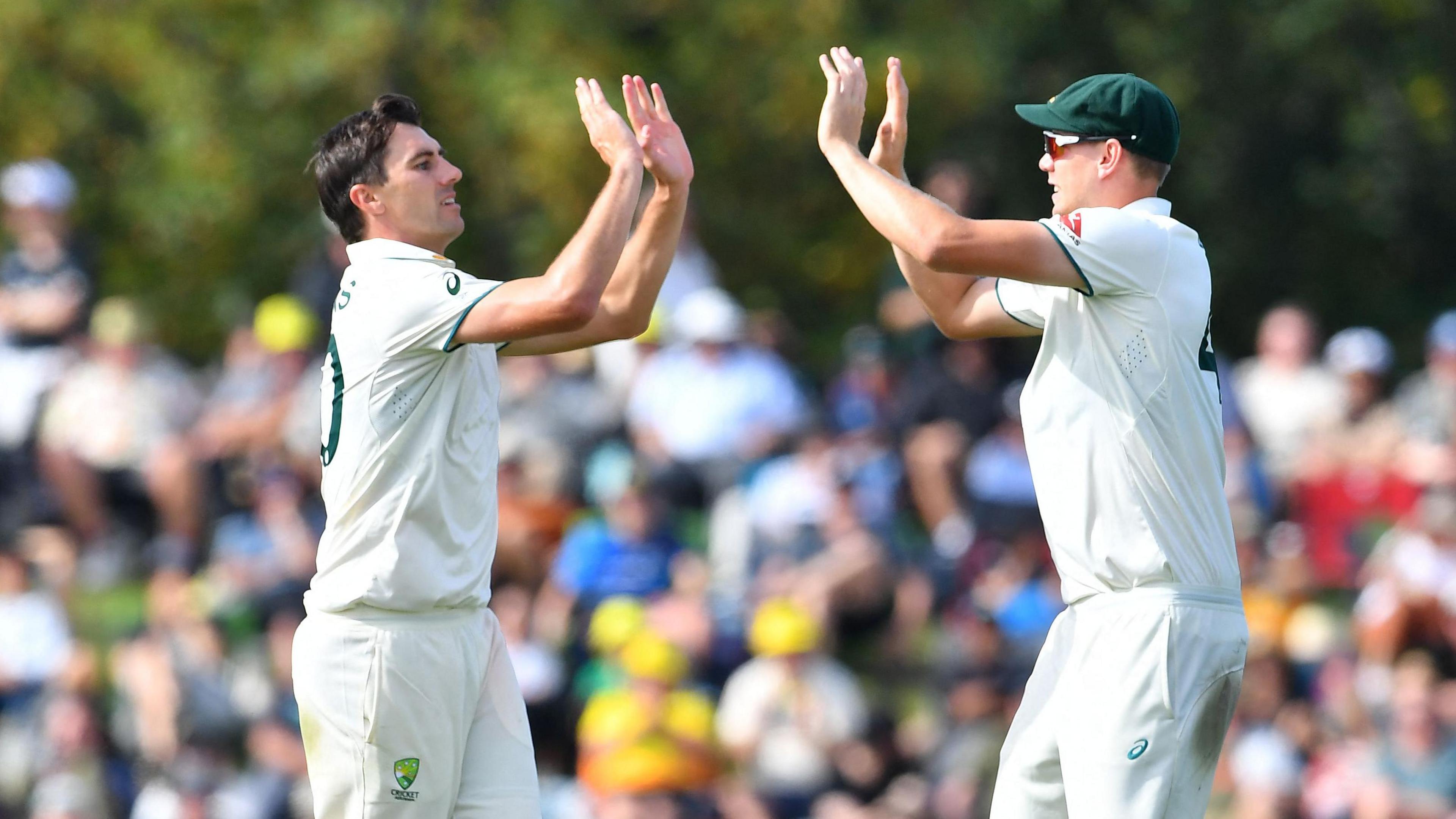 Australia's Pat Cummins (L) celebrates the wicket of New Zealand's Tim Southee with his teammate Cameron Green