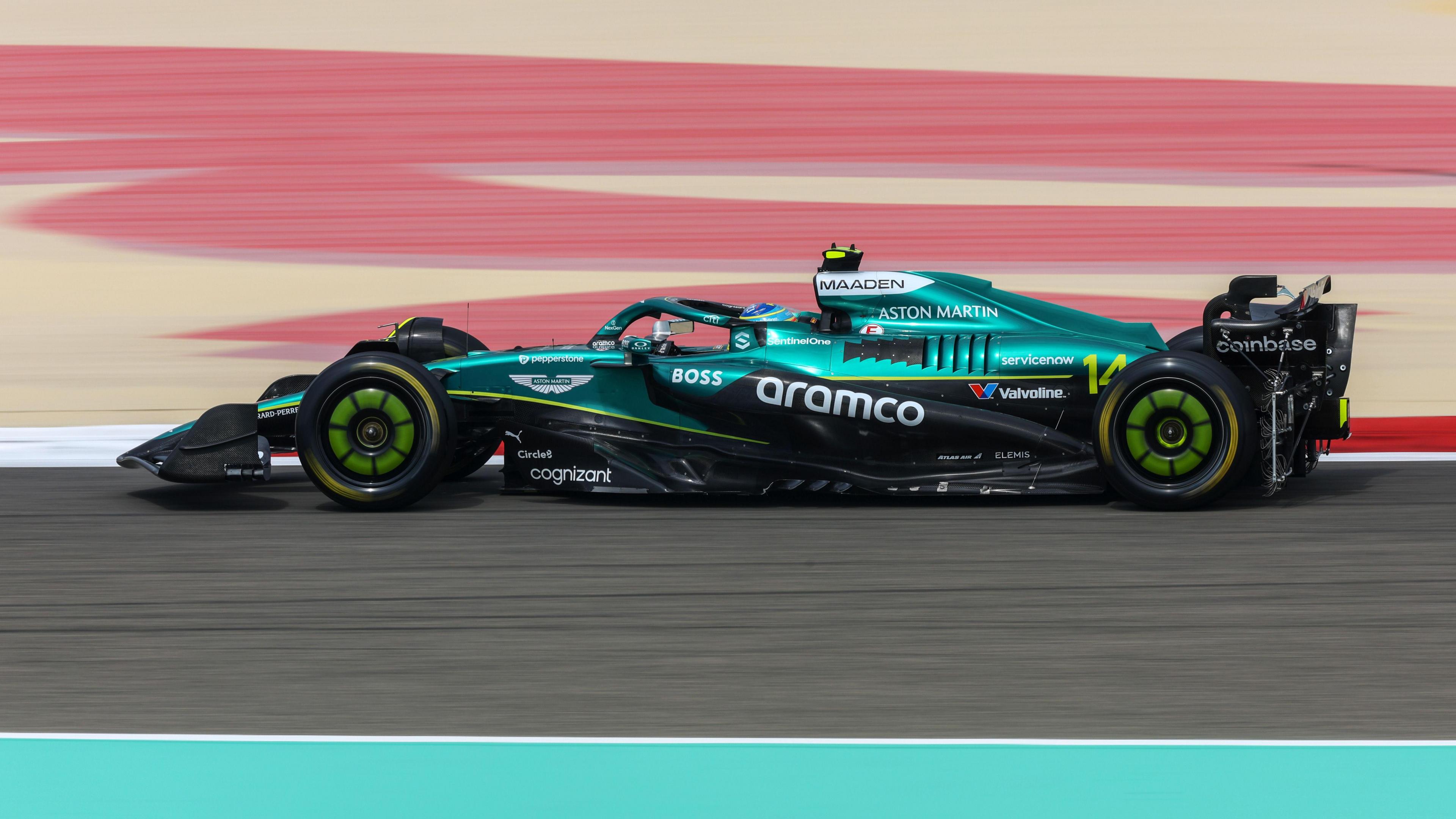 A green and black F1 car on a race track in Bahrain.