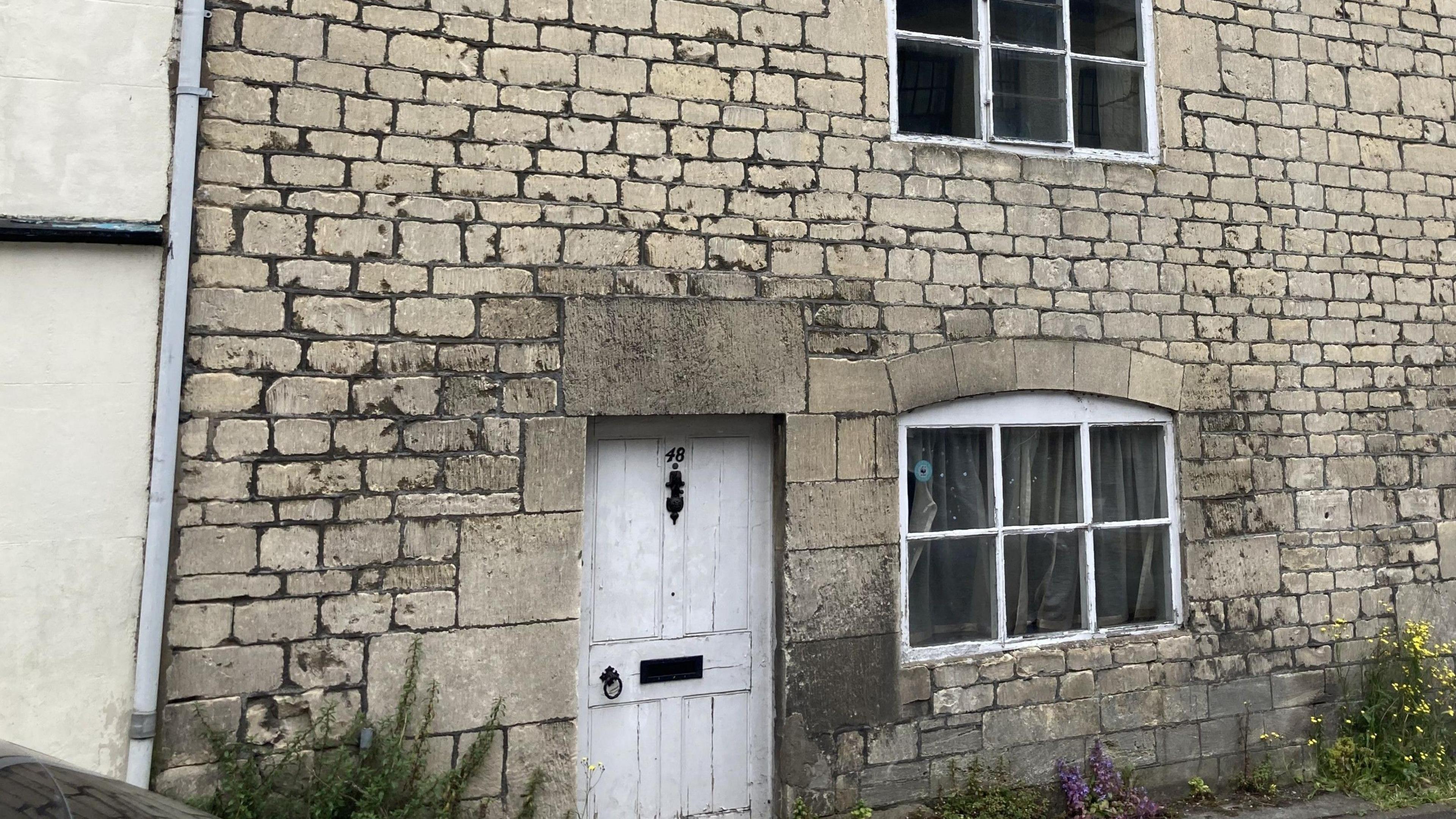 The entrance to the Lower Street house gifted to Emmaus. The outside is made of light coloured brick and has a white wooden door with a long, dark, metal knocker.