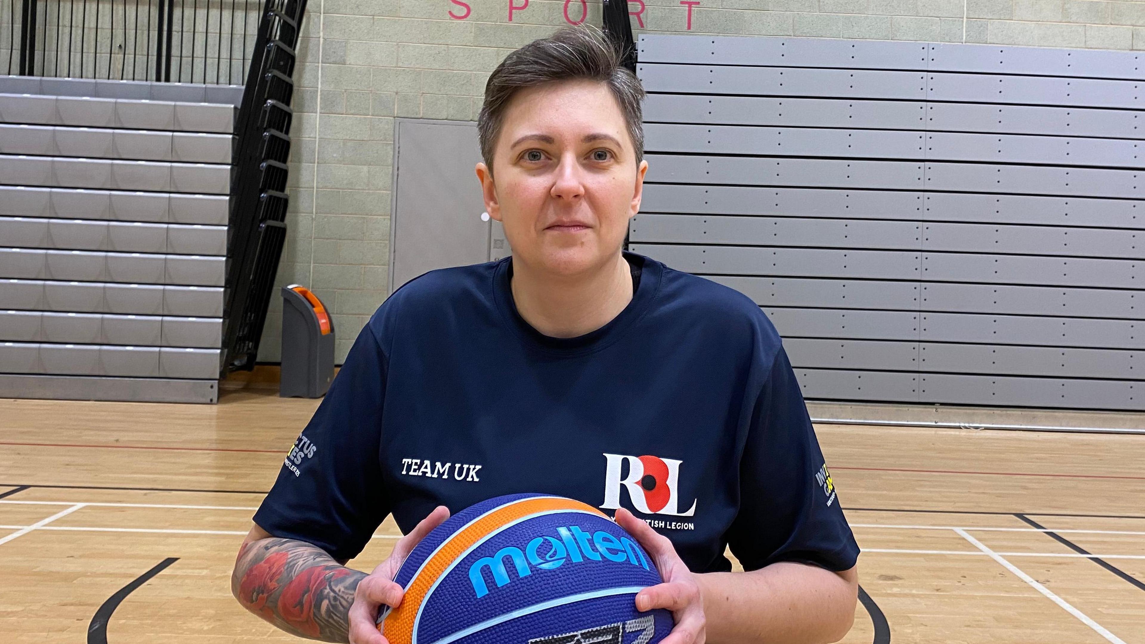 Liz Lee holding a basketball and wearing a navy Team UK t shirt 