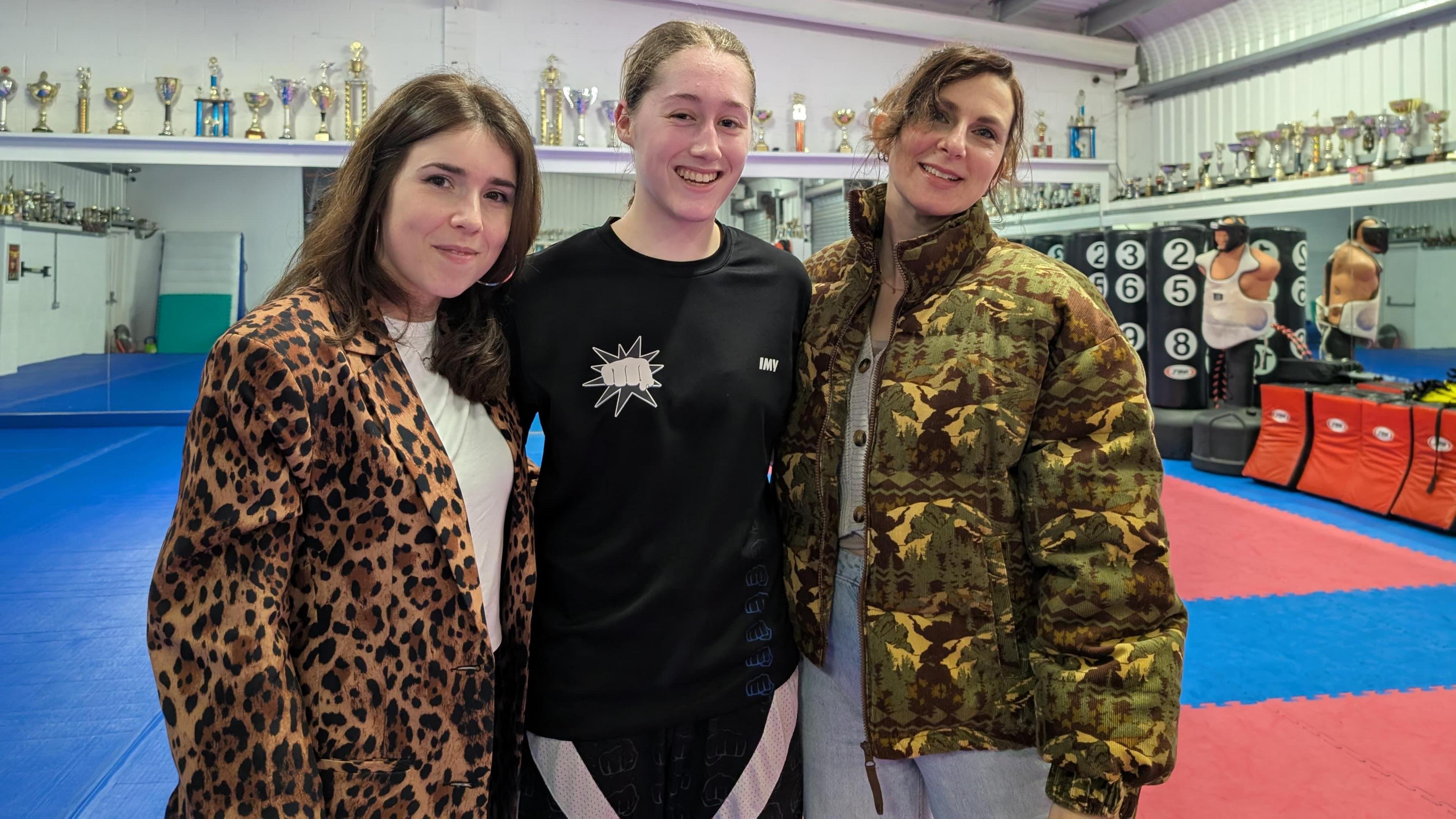 Imogen stood inbetween her teacher Sian on the left, wearing a leopard print coat, with Becky on the right wearing a camouflage coat.