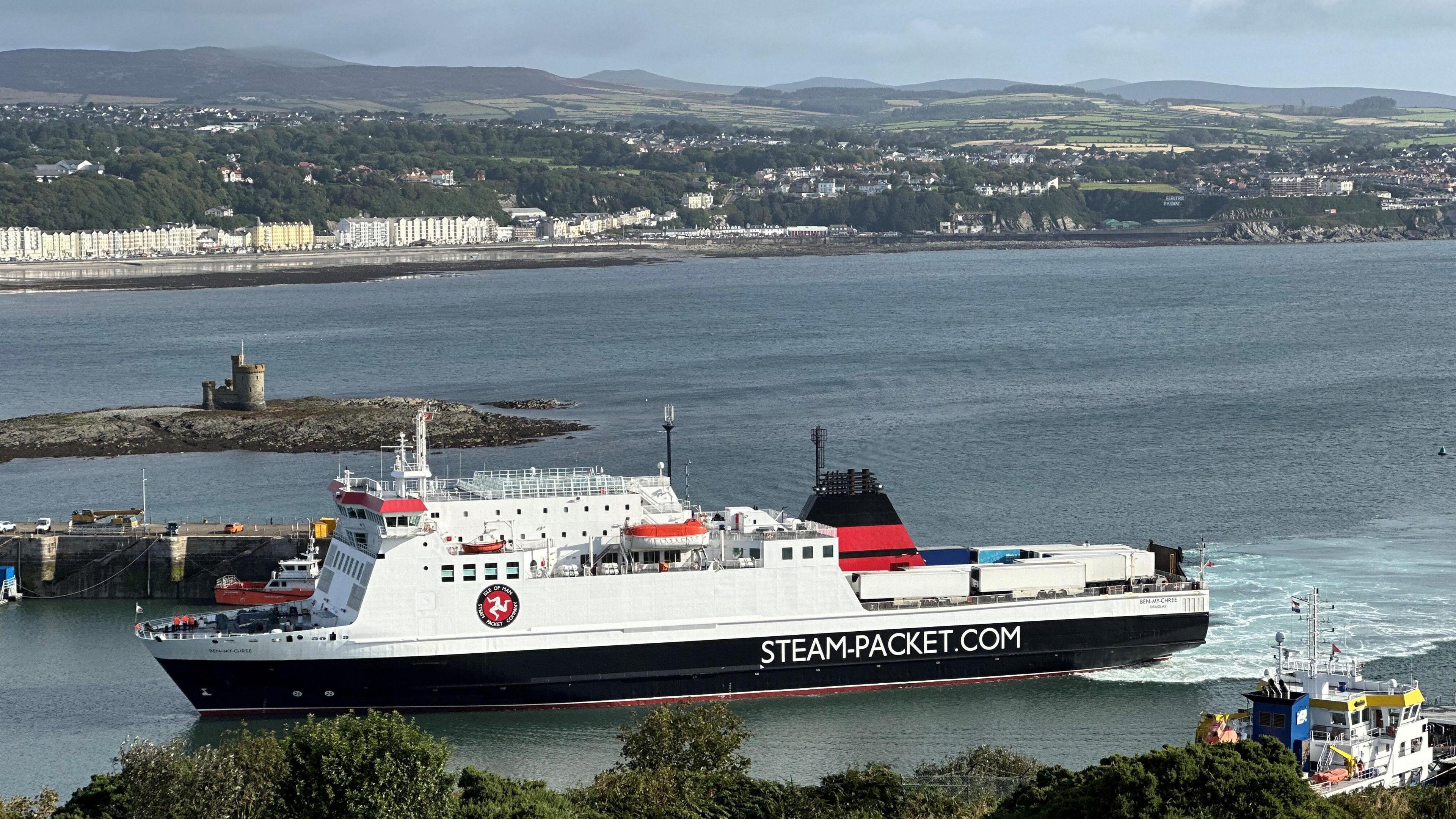 The Ben-My-Chree entering Douglas Harbour. It is white, black and red and has the Steam Packet logo on the side. Douglas Bay the Tower of Refuge can be seen behind it.