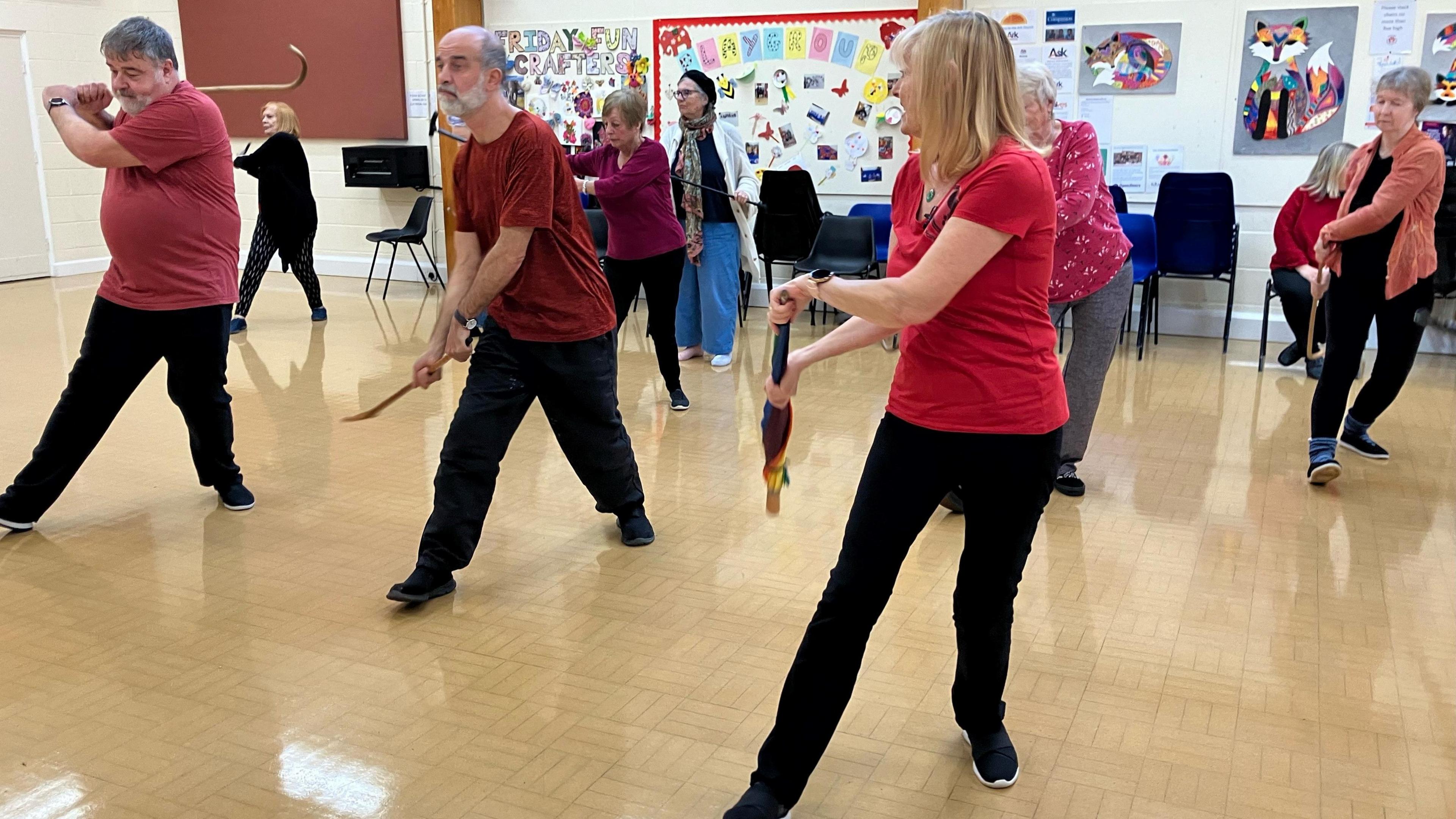 People in Tai Chi class wielding walking sticks