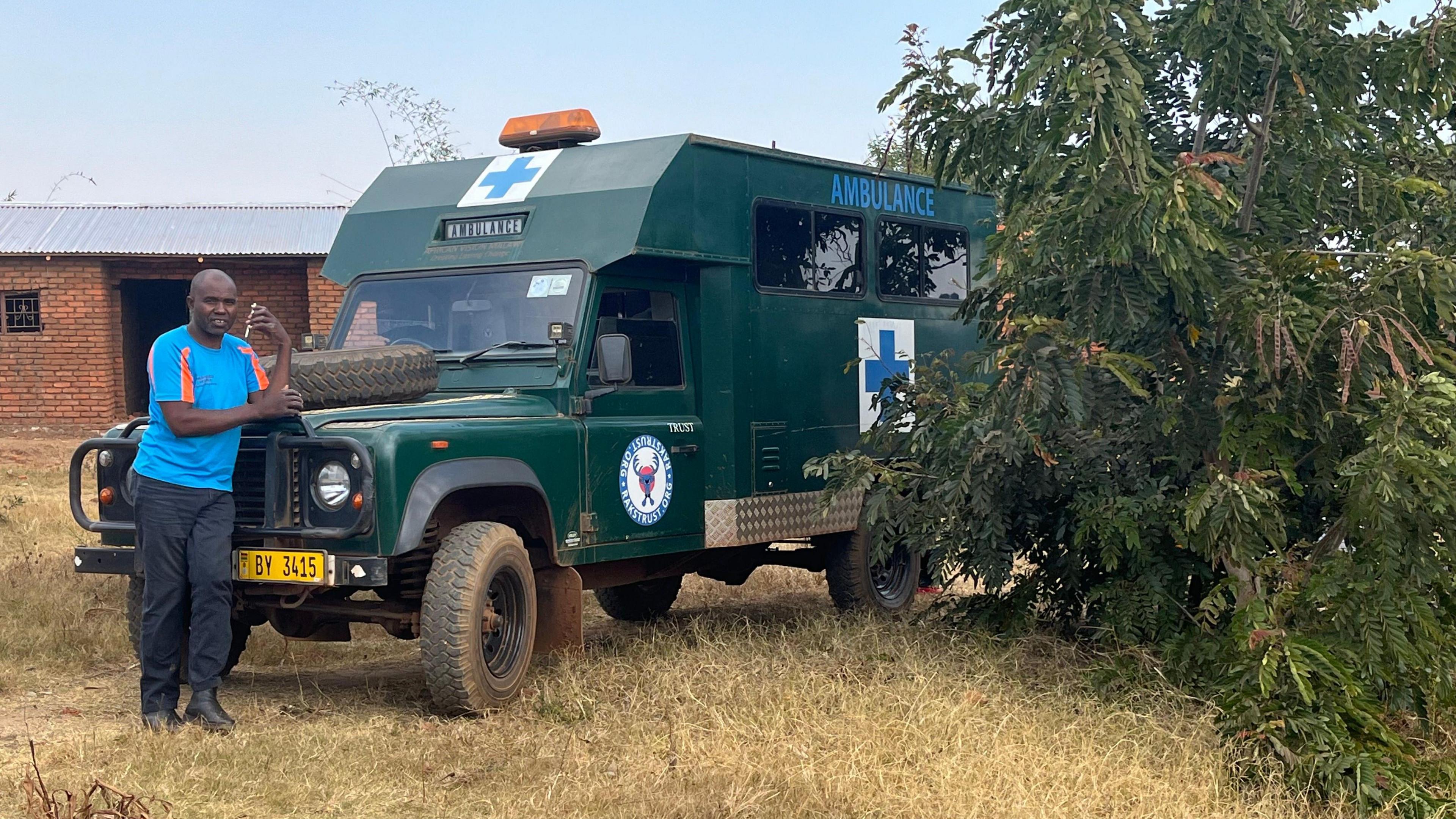 The driver of the ambulance leans on the bonnet of the converted ex-RAF vehicle