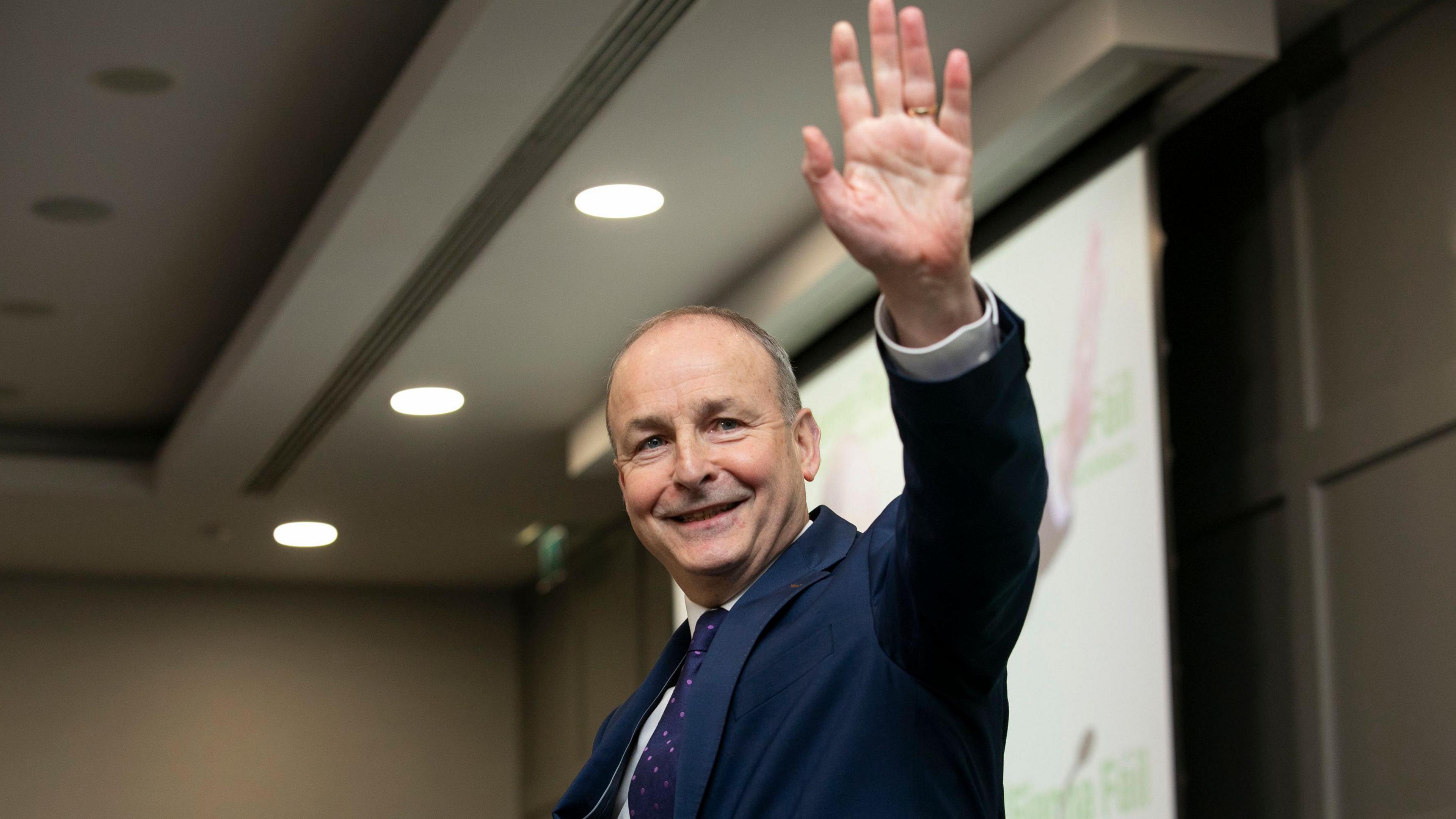 The taoiseach (Irish prime minister) waves. He is wearing a dark coloured suit. 