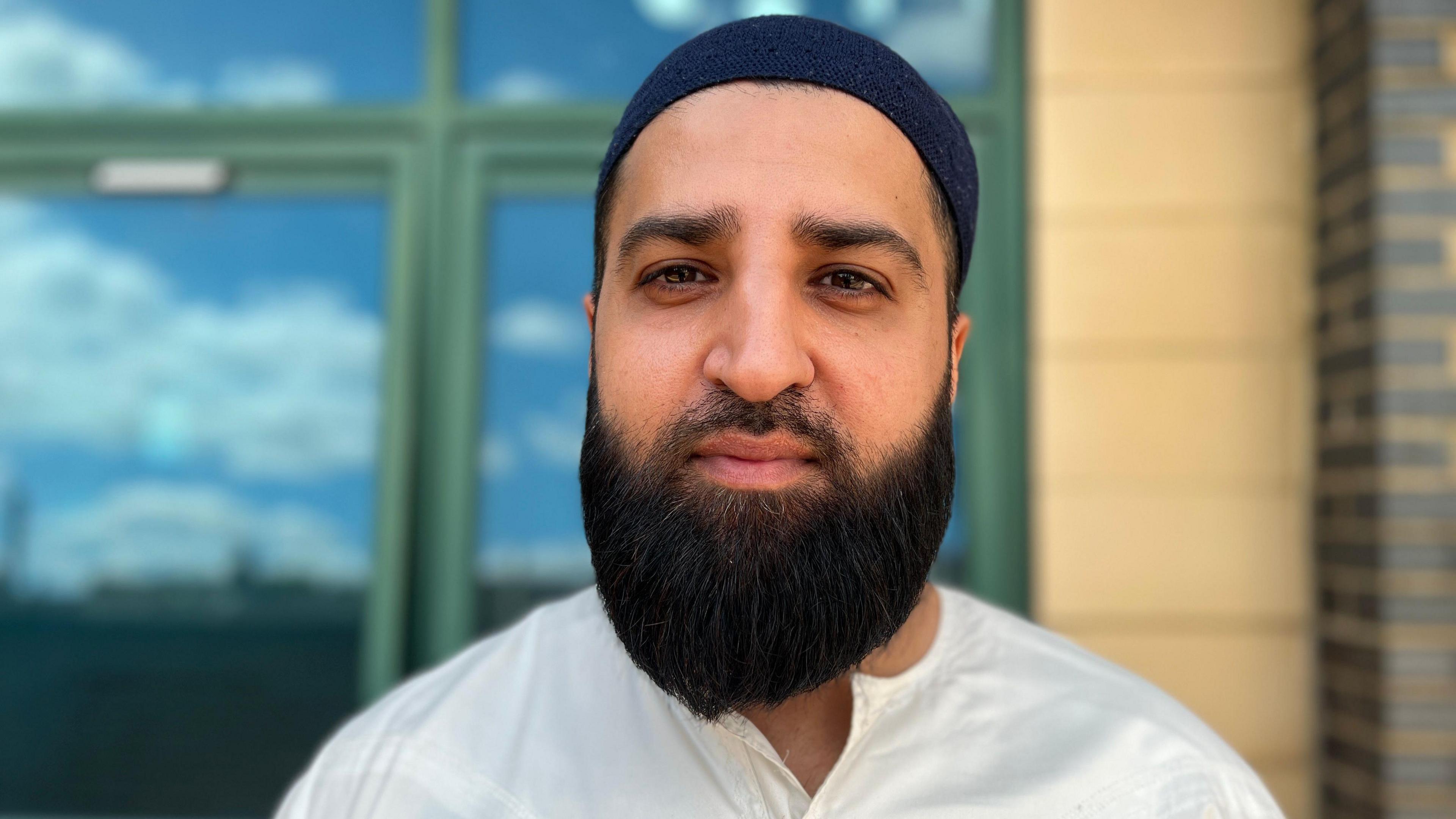 Sharaz Khan wearing a blue skull cap looking into the camera 