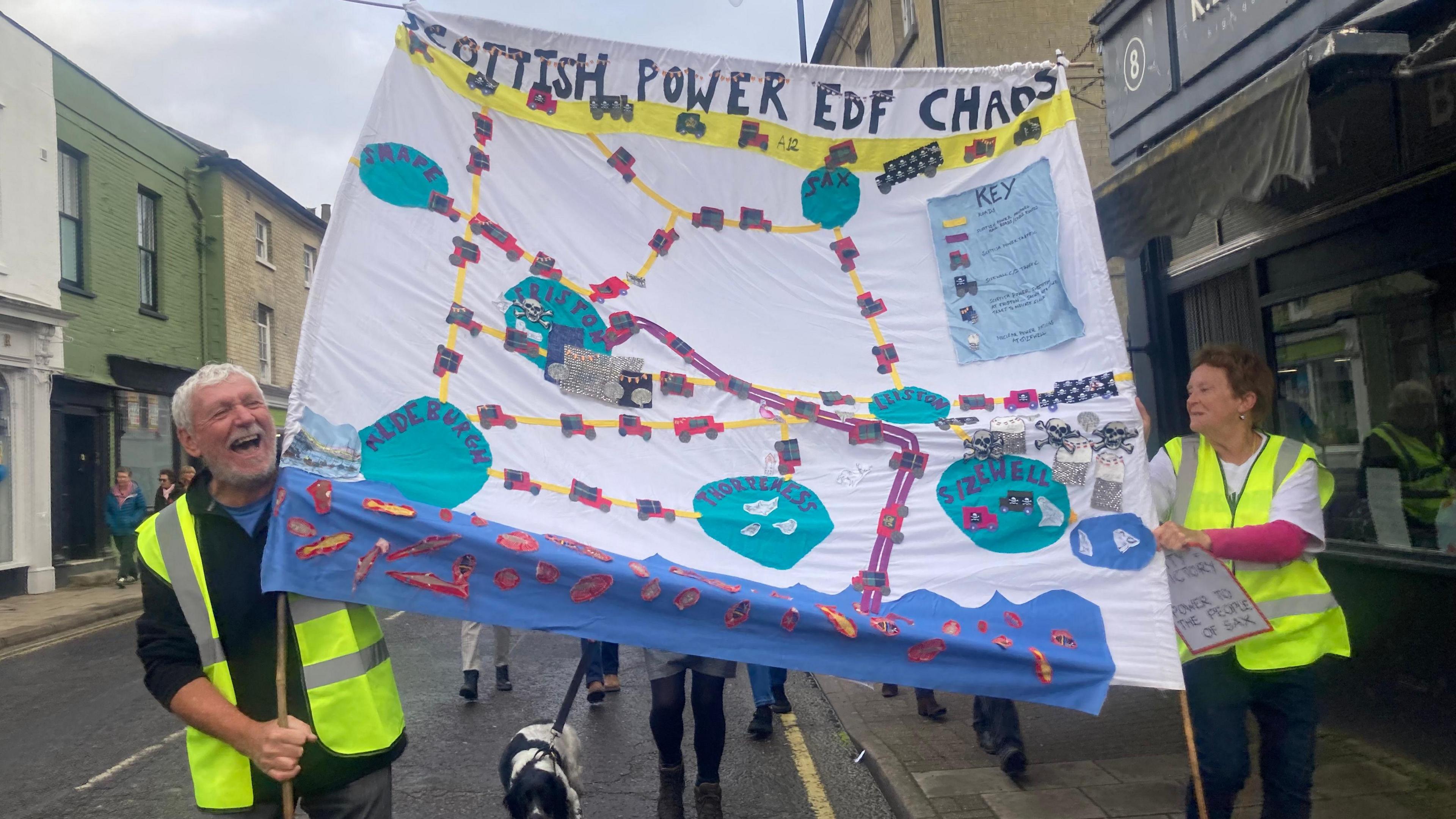 Campaigners wearing green high-visibility jackets holding a poster