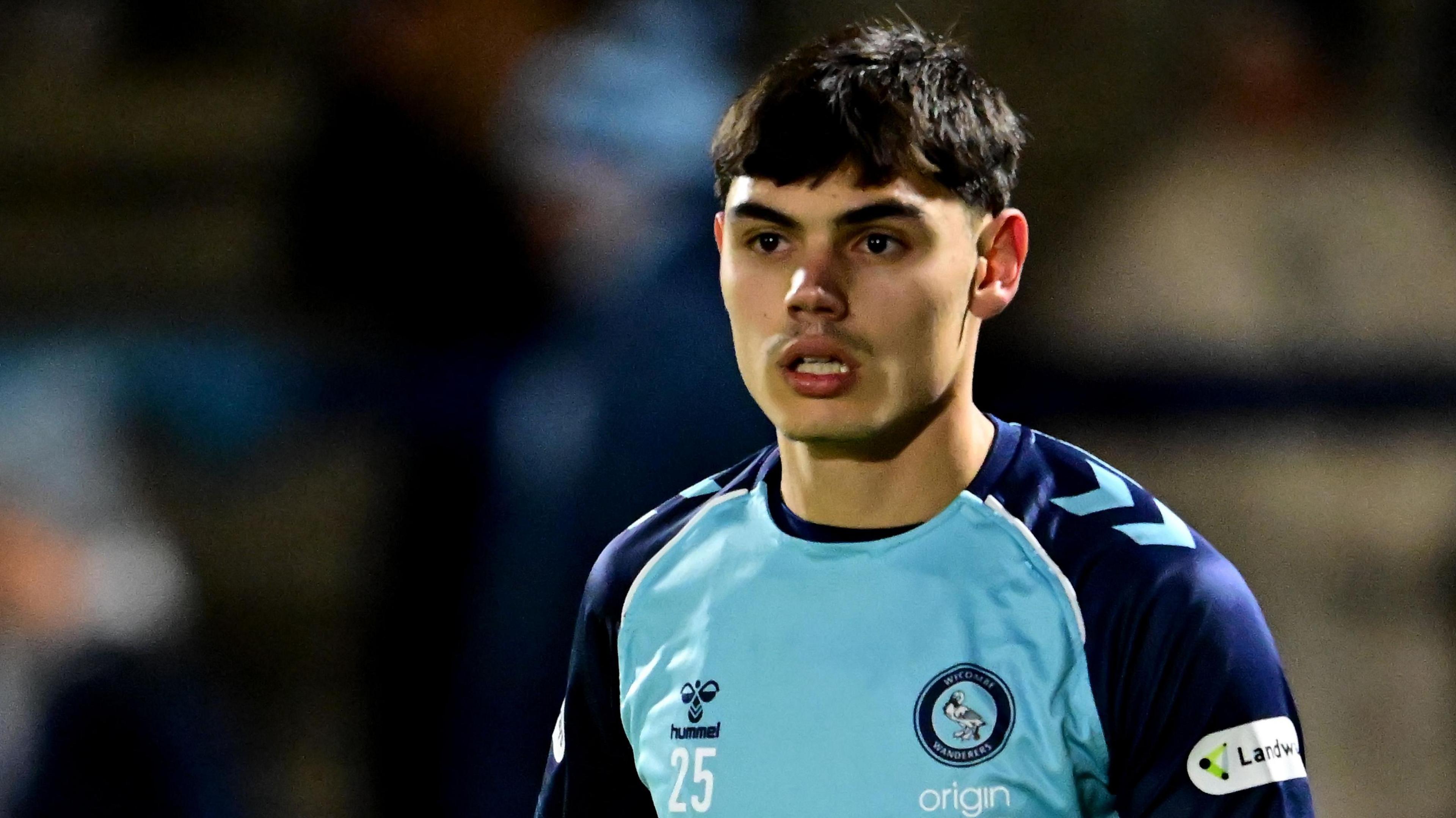 Declan Skura in action for Wycombe wearing a home shirt of sky blue front with dark blue sleeves.