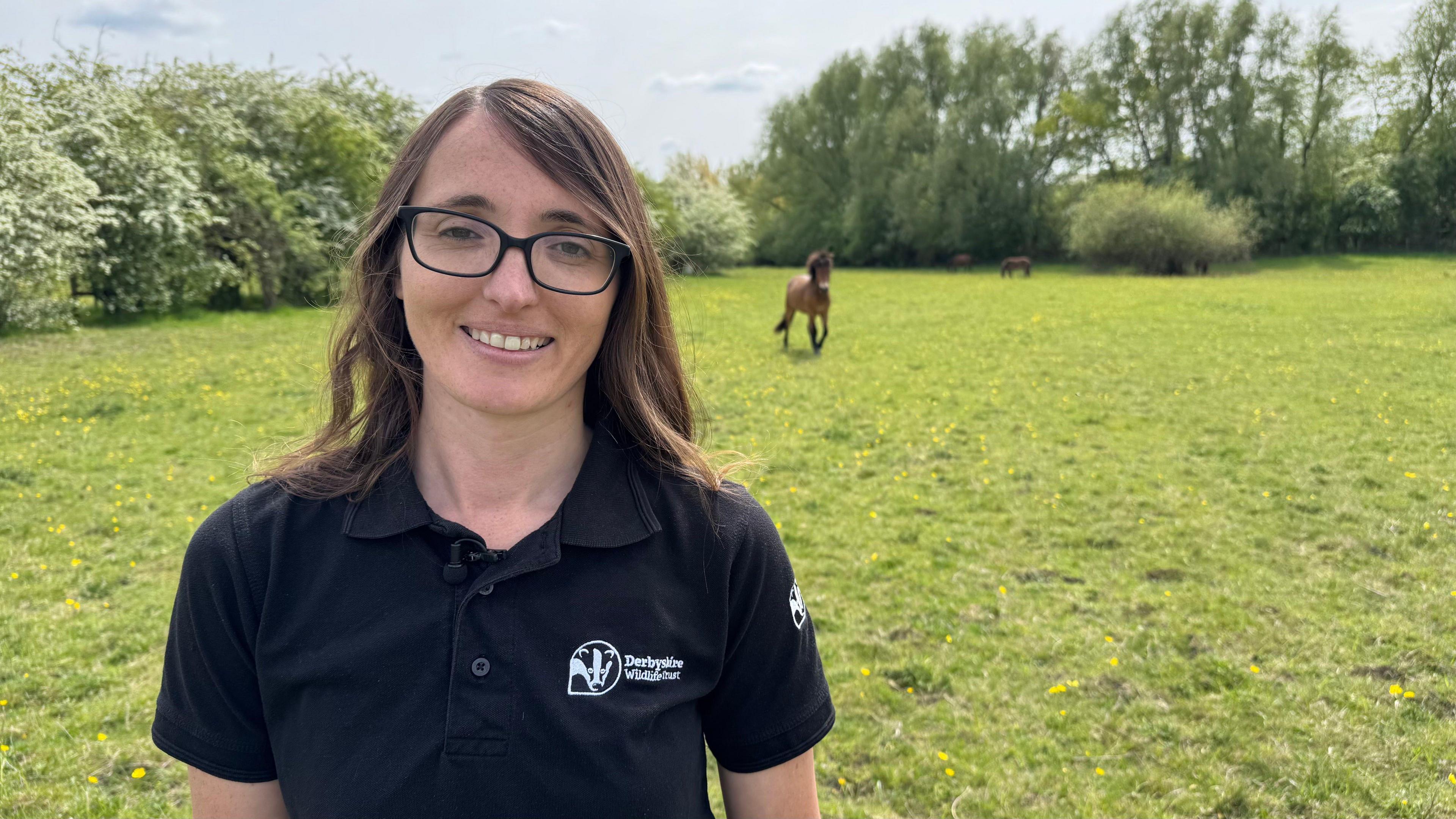 Derbyshire Wildlife Trust's Katie Last stands in a field with an Exmoor pony behind her