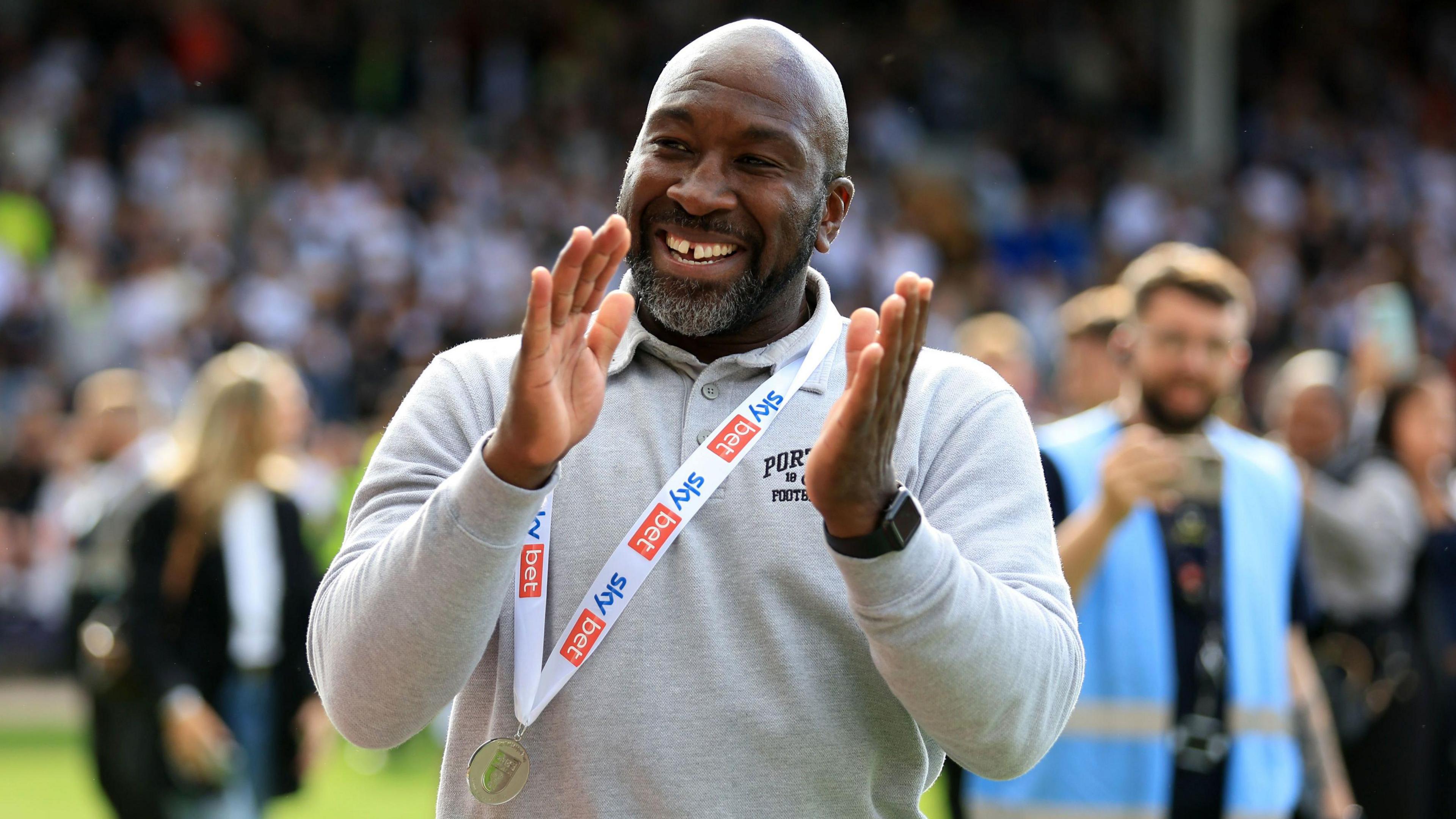 Port Vale boss Darren Moore wears a League Two promotion medal around his neck as he claps fans after the final match of the season