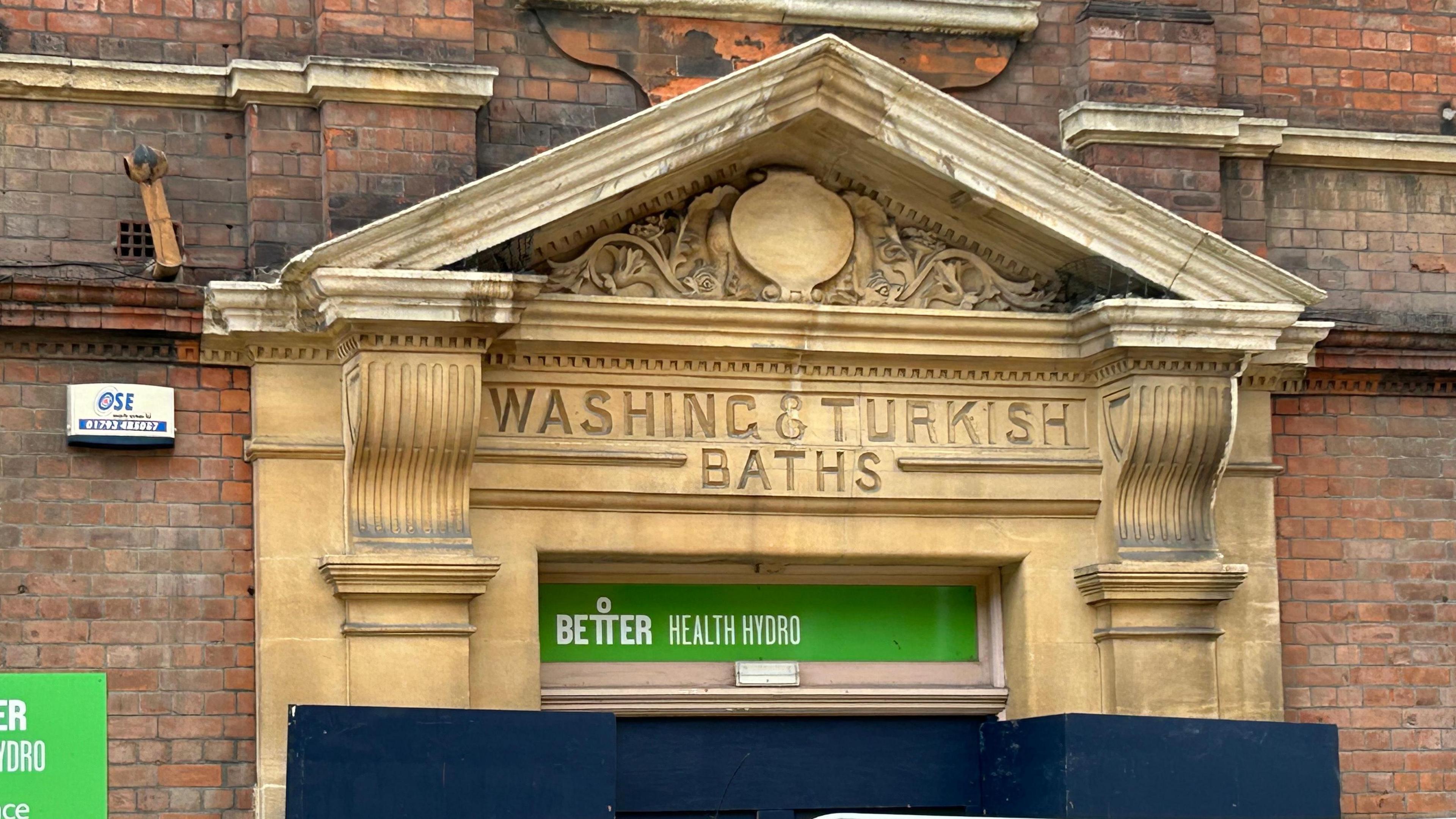 Ornate brick pillars and frontage which states 'Washing & Turkish Bath' on a red-brick background.