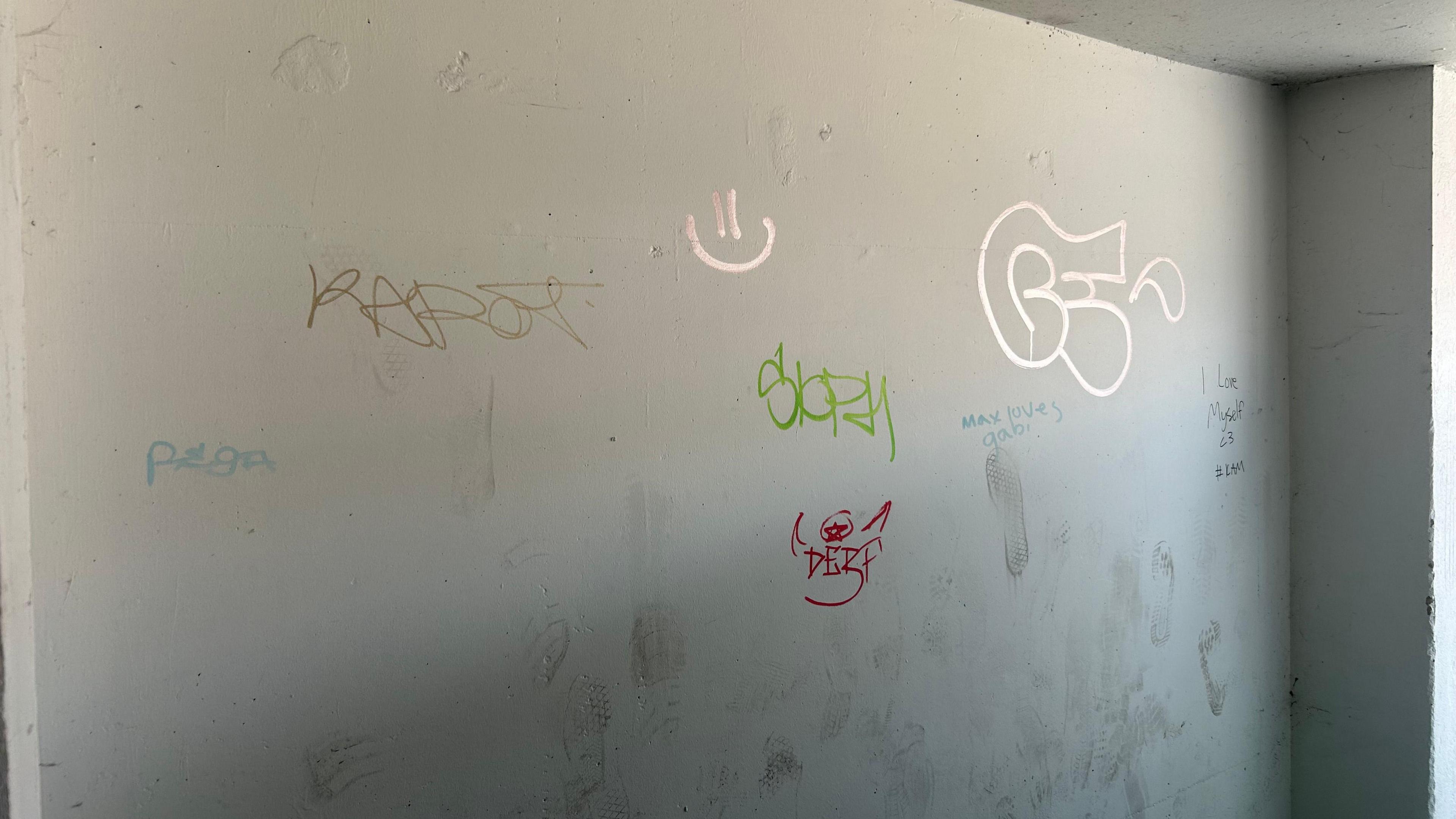 Graffiti tags on an off-white wall