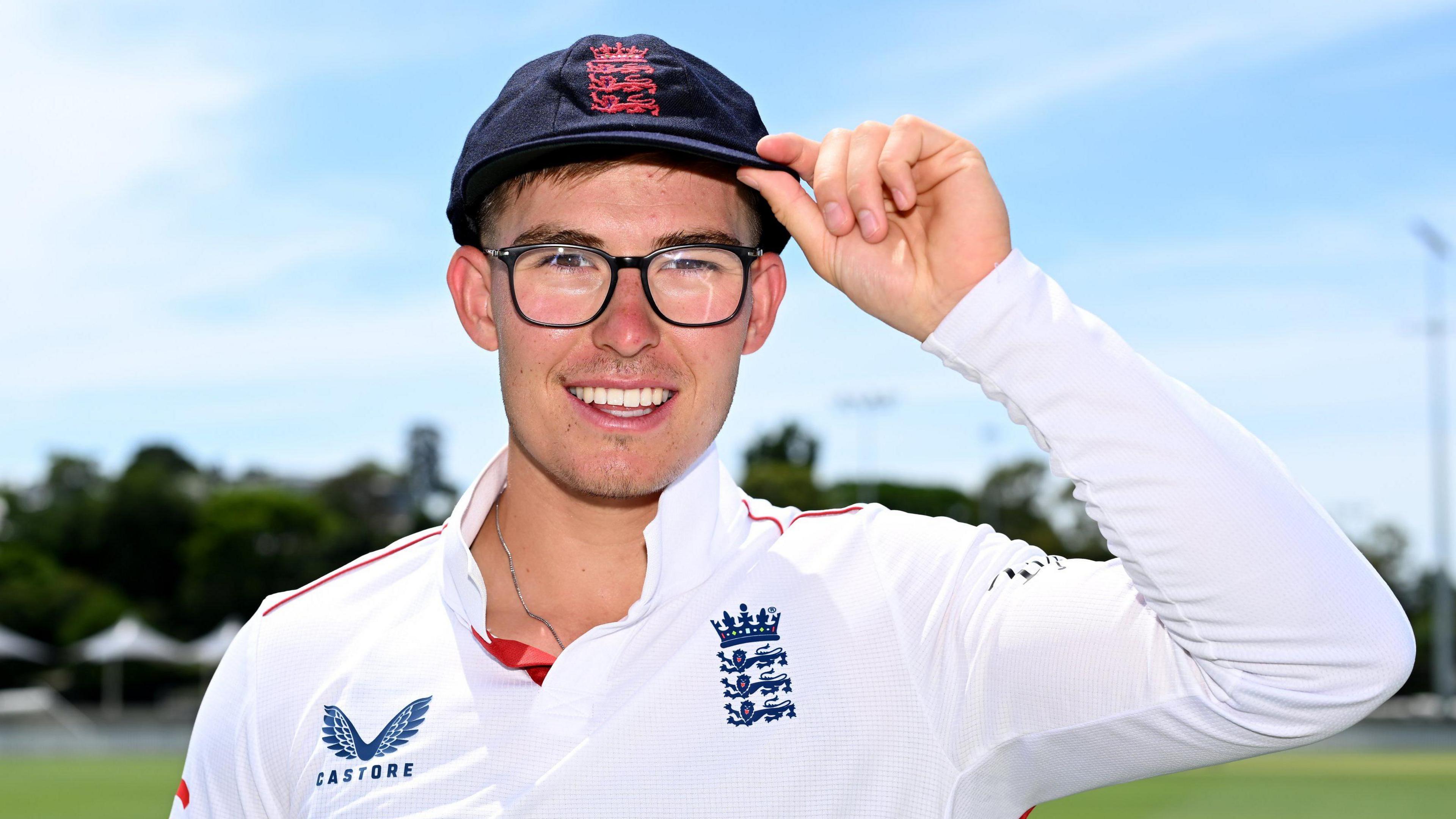 England Lions batter Asa Tribe smiles while touching the brim of his cap