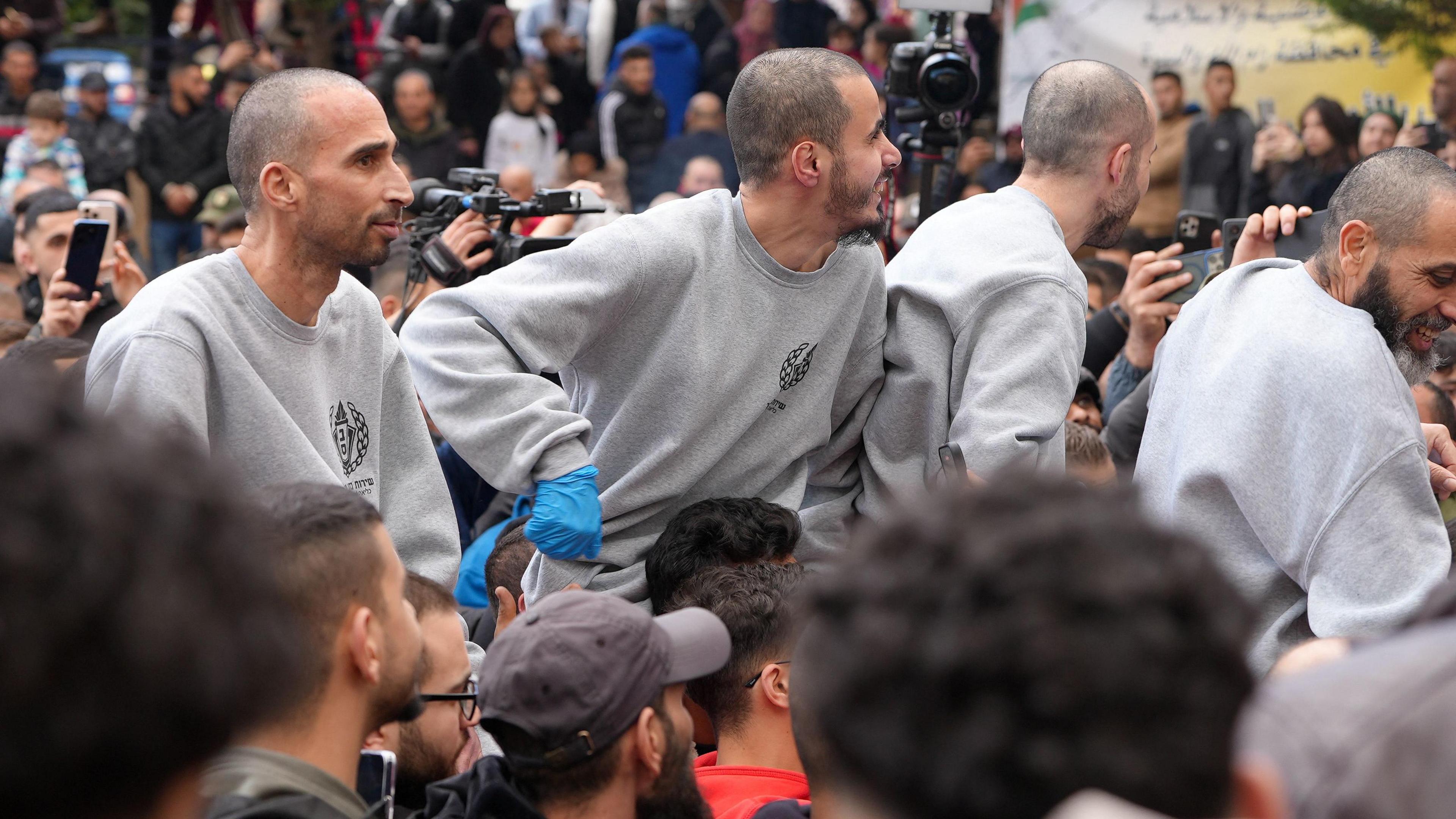 Four freed Palestinian prisoners wearing matching grey sweatshirts are greeted by people after being released from an Israeli jail in Ramallah, in the occupied West Bank.