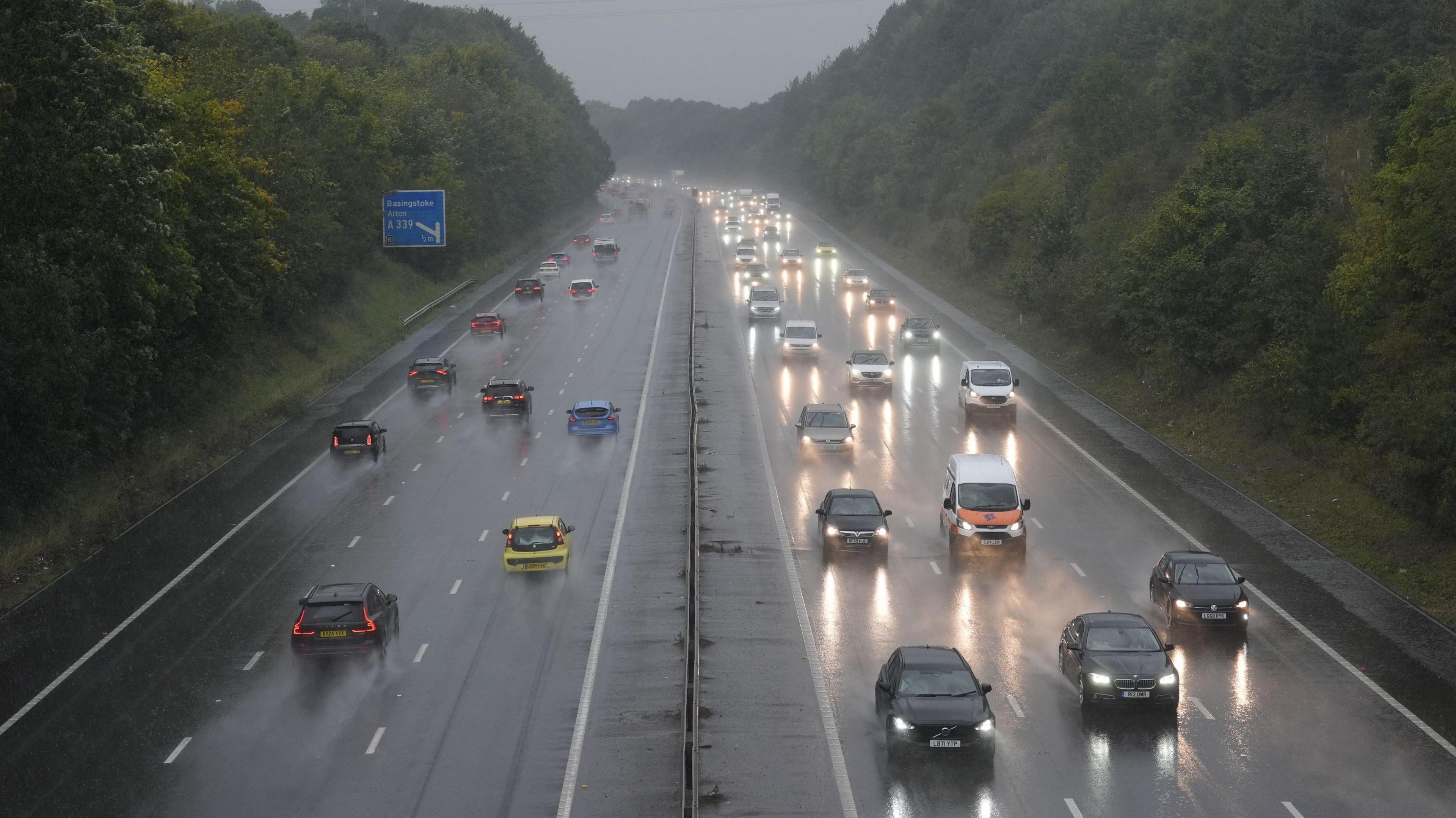 A motorway, with oncoming traffic and traffic heading away, side by side, it is a wet December day