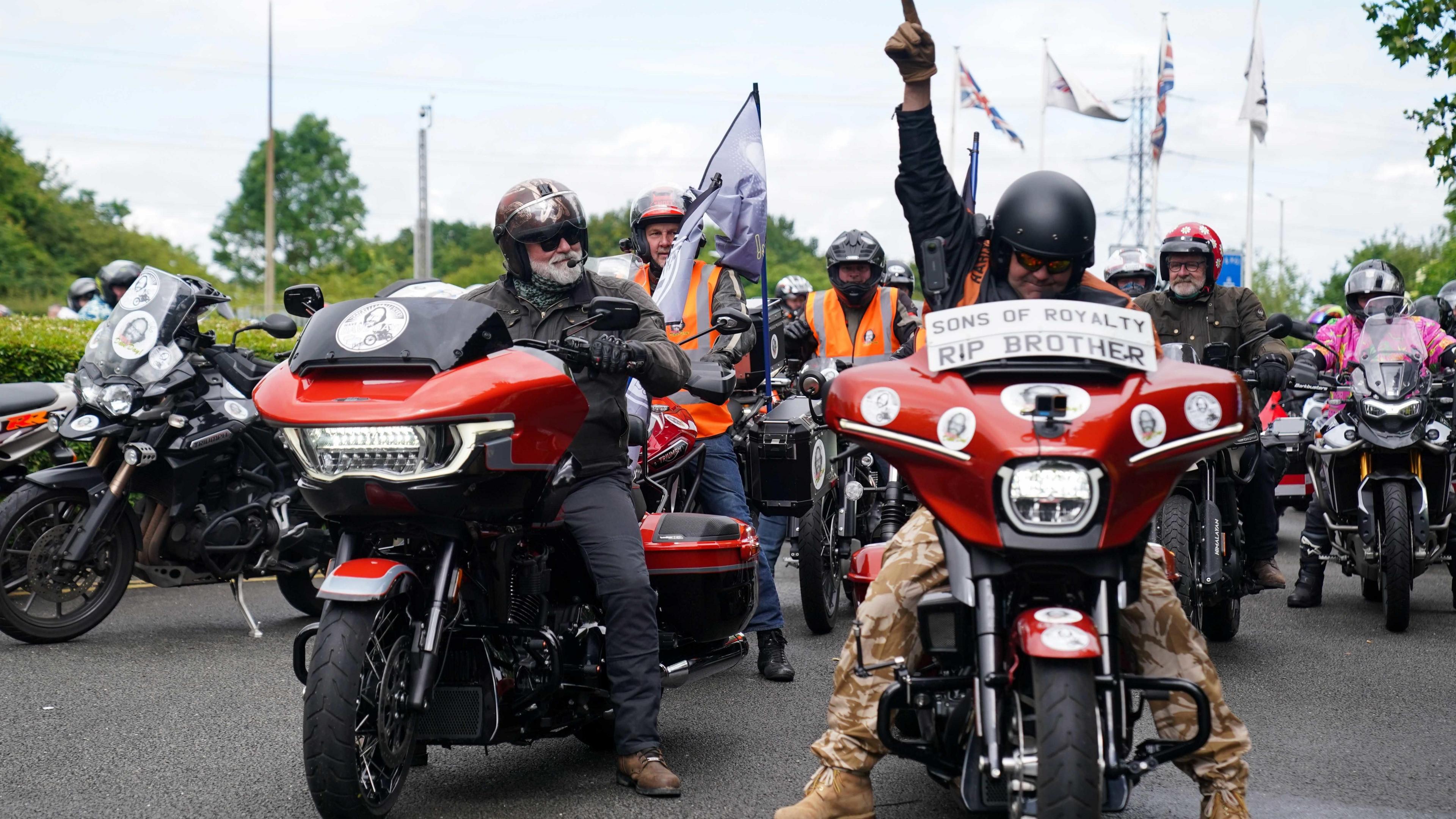 Hairy Biker Si King on his motorbike at the National Motorcycle Museum in Solihull. Next to him is another rider who is pointing his index finger in the air. Behind them are a group of more bikers taking part in a ride from London to Barrow in Cumbria.