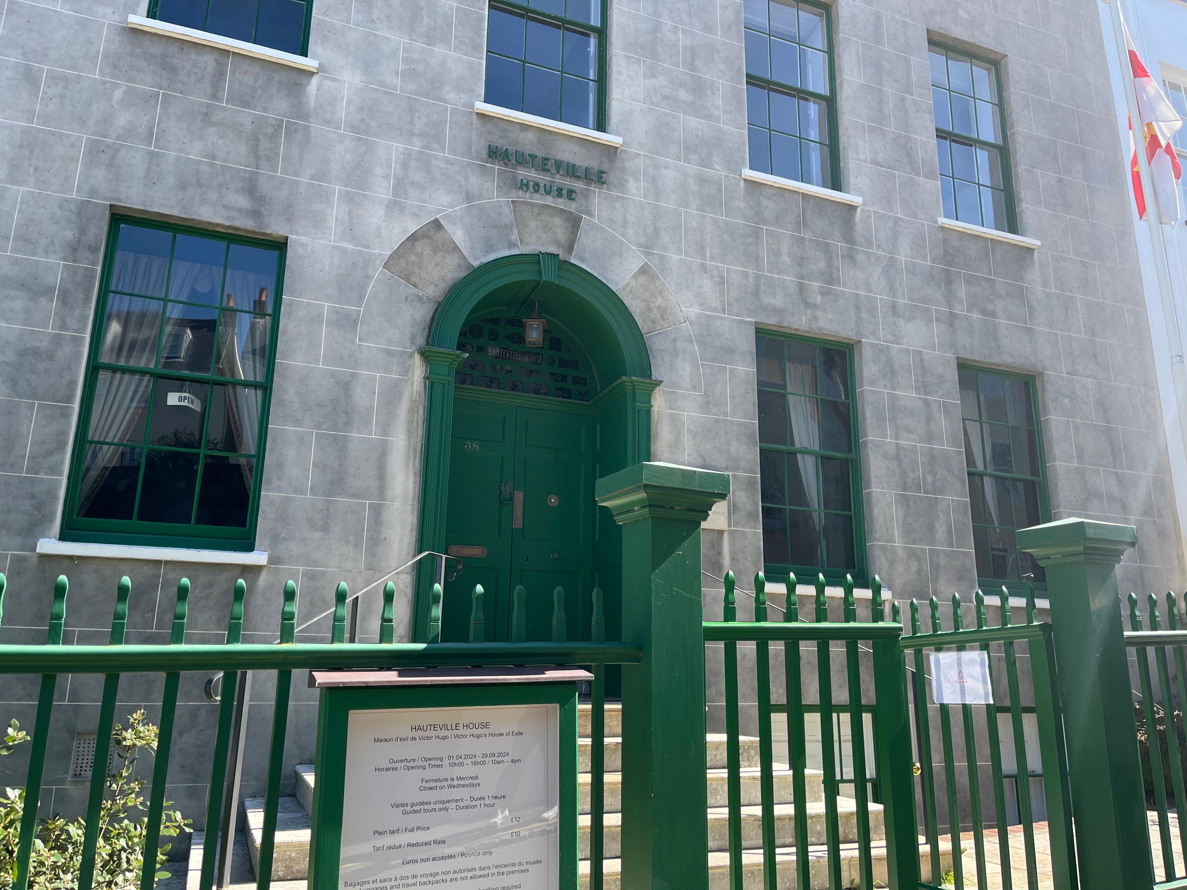 A grey house built of stone, with a green door and railings. A sign above reads Hauteville House.