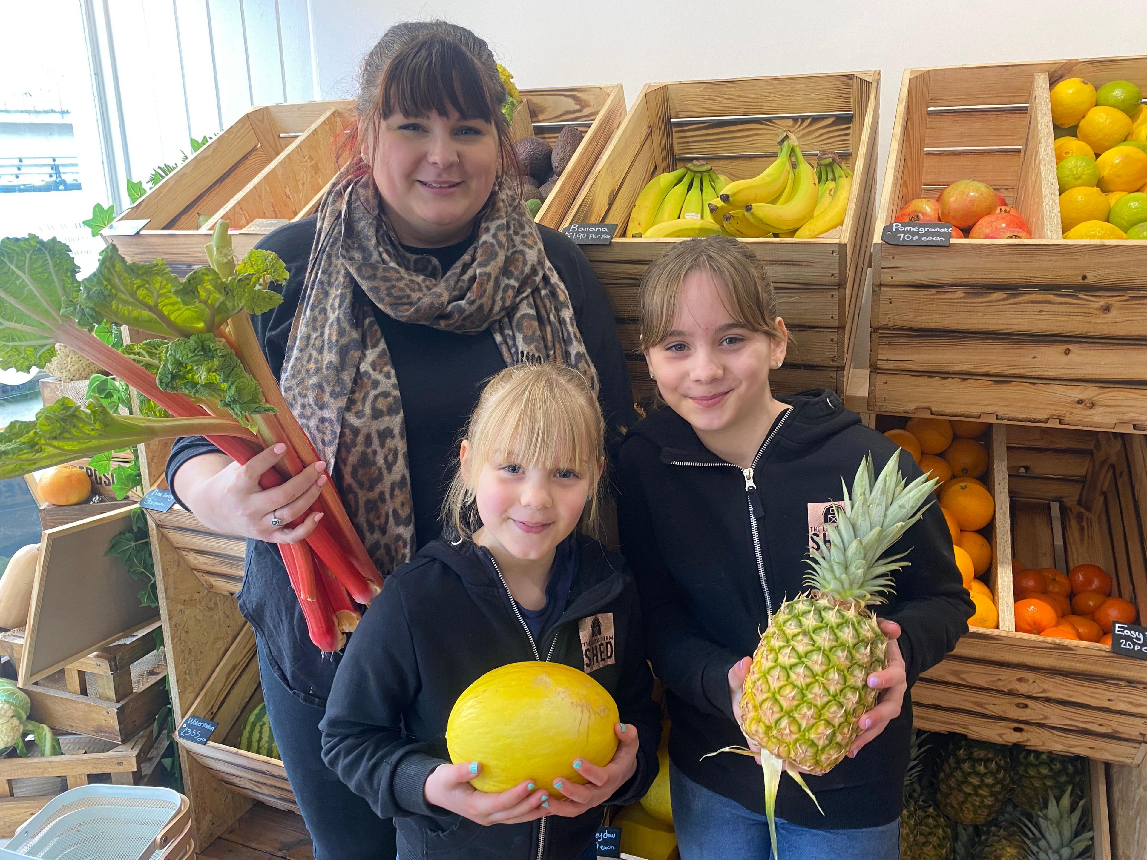 Mother Jordan stands in the Little Farm Shed shop with daughters Rosie and Laurel