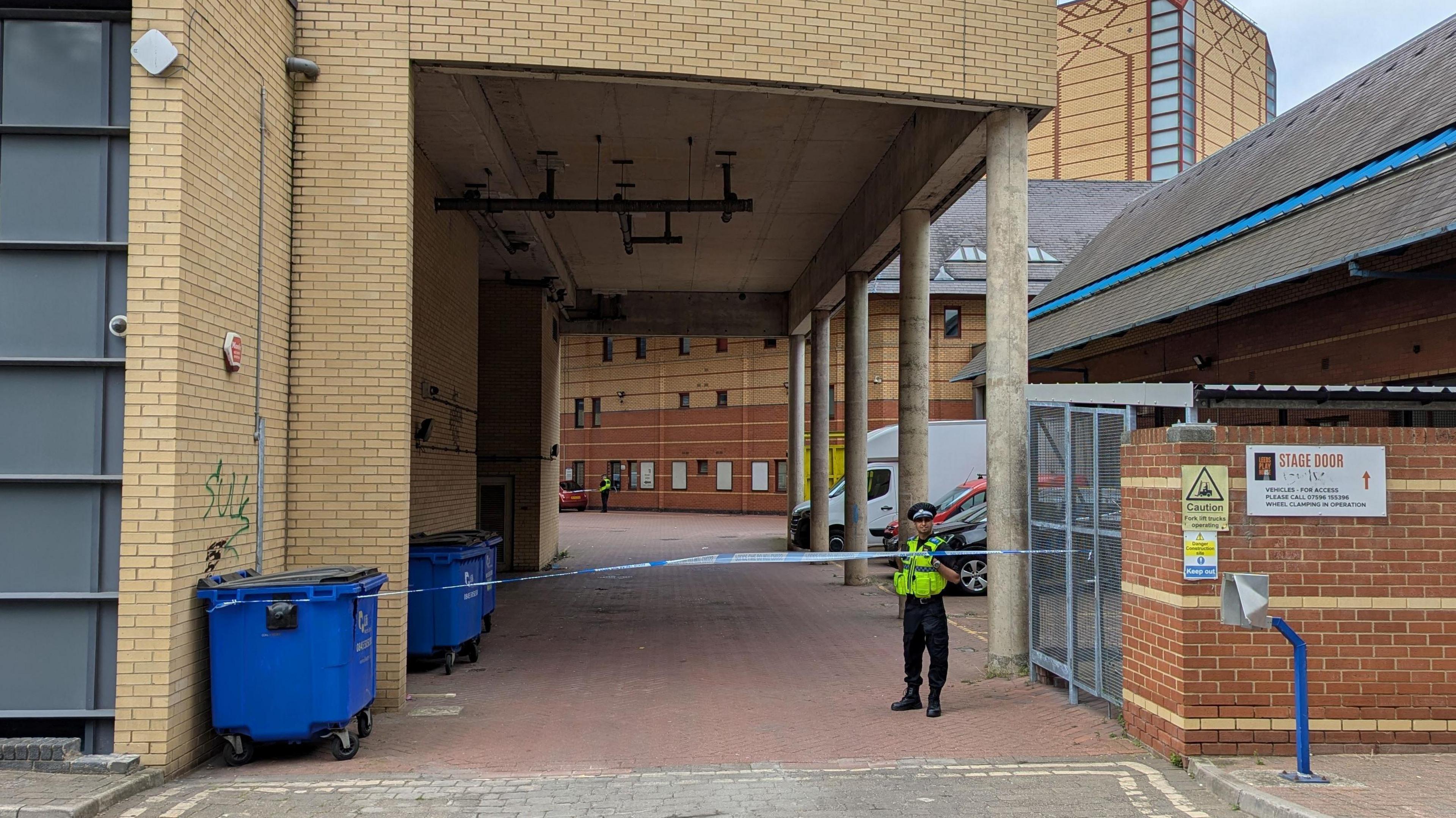 A police officer stands guard next to some police tape.