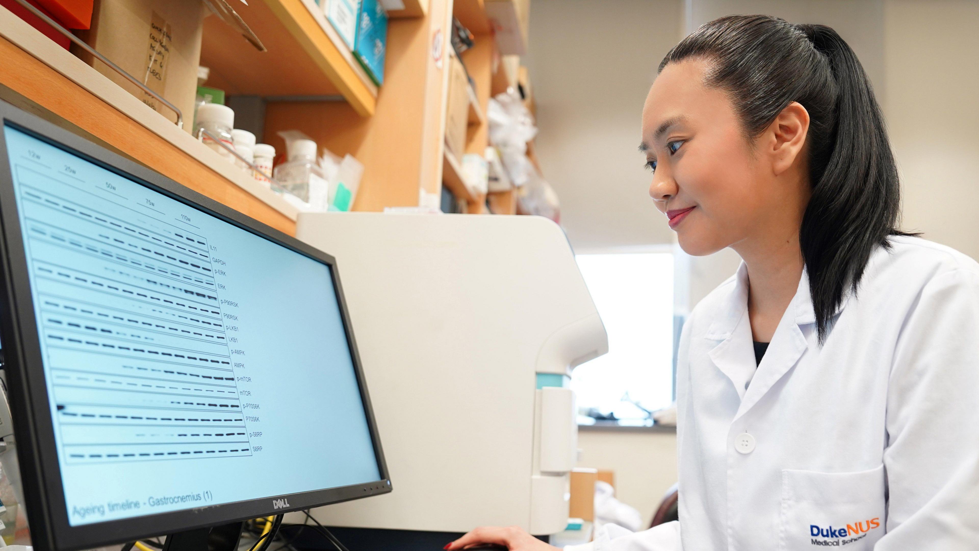 Prof Anissa Widjaja wearing a lab coat and analysing the experimental data