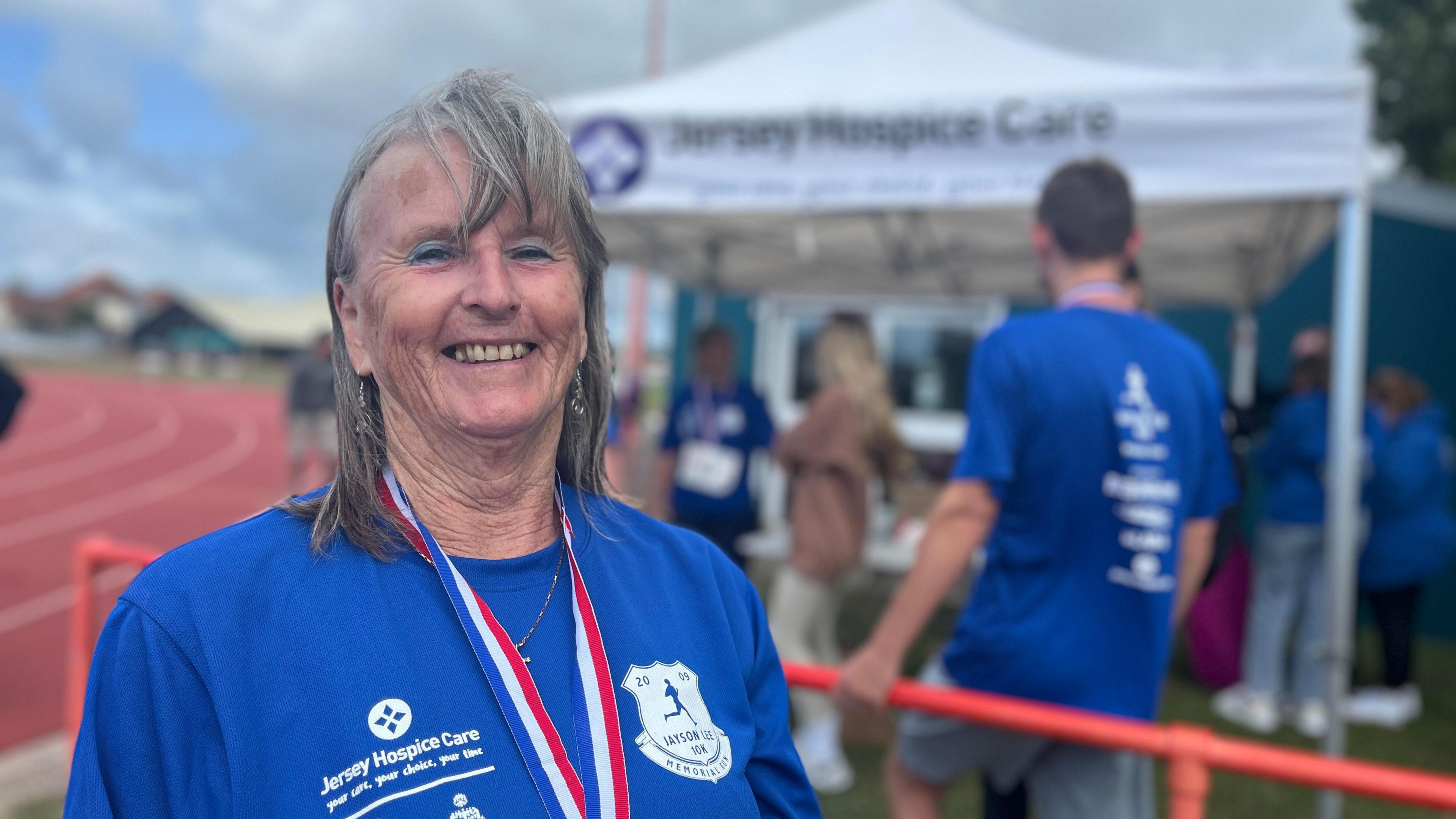 Margaret Lee smiling at the camera with a blue t-shirt on and a medal round her neck.