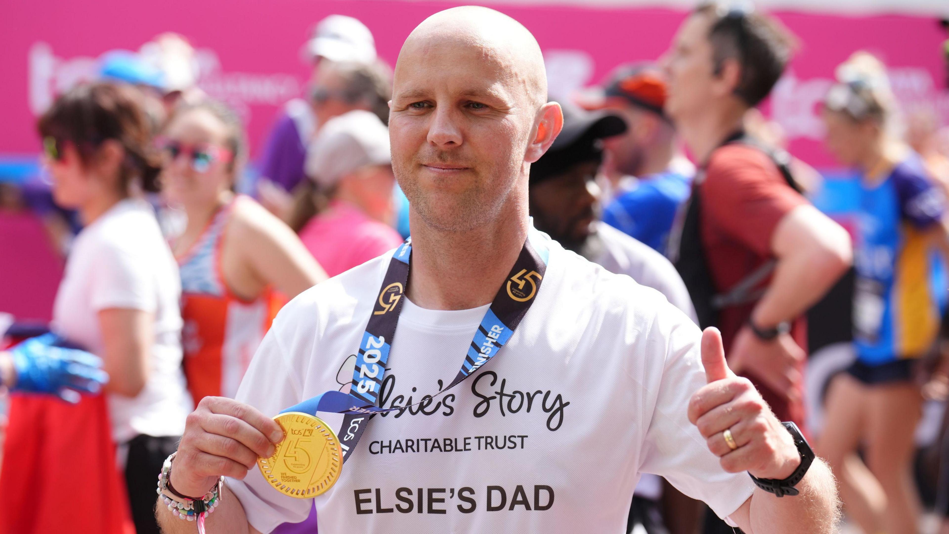 David Stancombe, the father of Southport attack victim Elsie Dot, holds up his finishers medal and flashes a thumbs up after crossing the finish line of the London Marathon