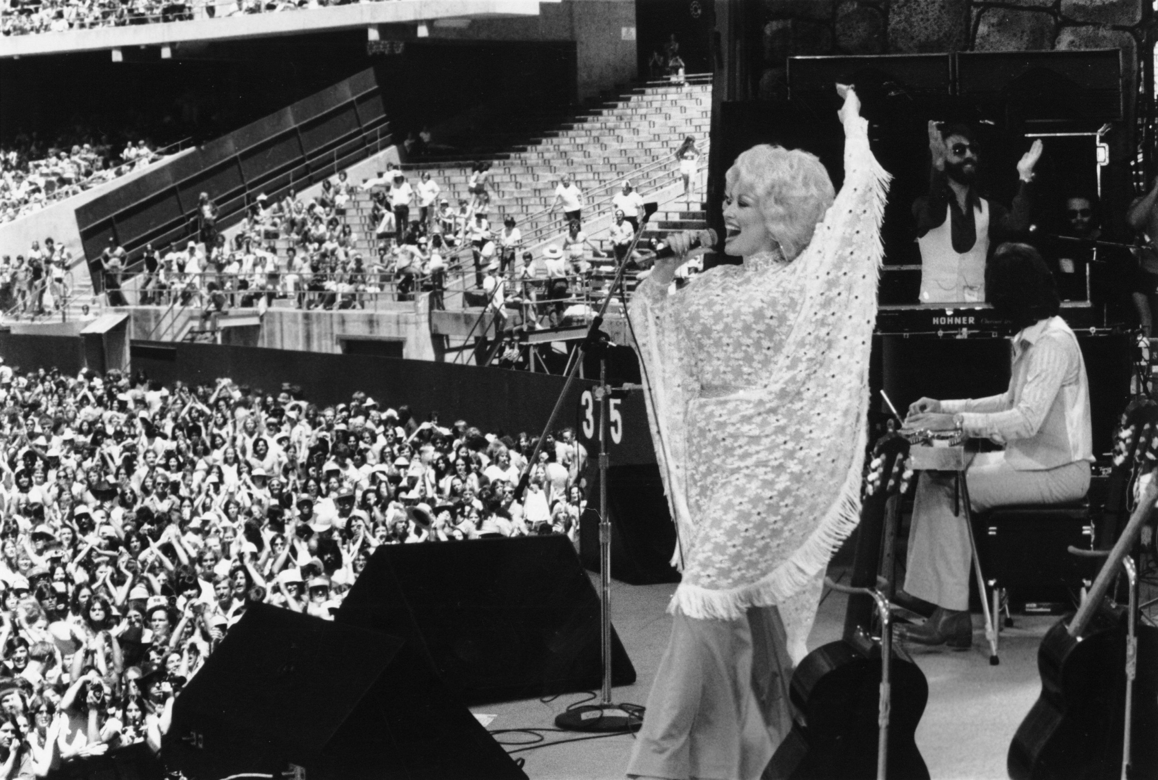 Parton performs on stage in 1978, in a pale shawl and before a big crowd.