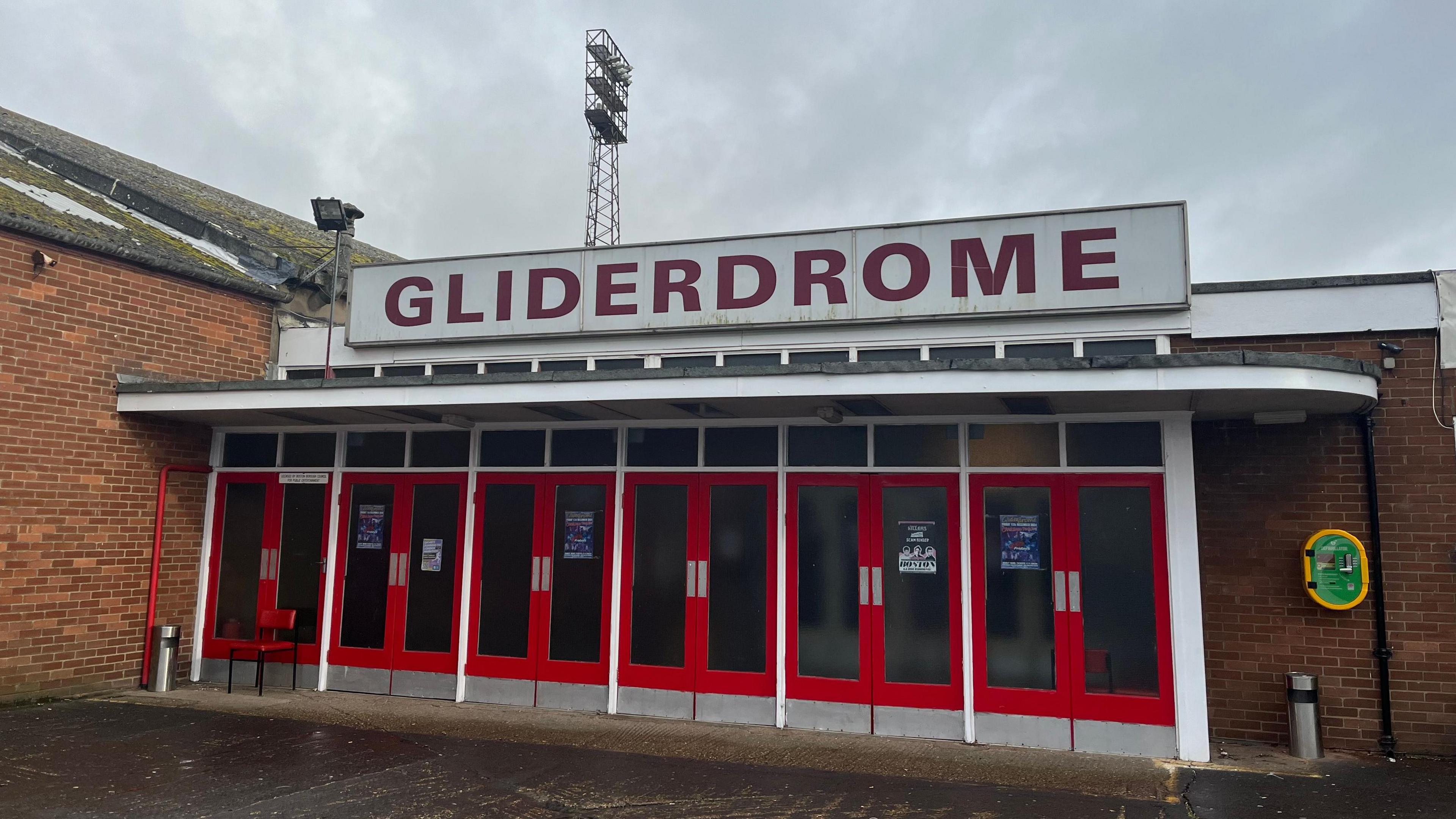 The front of The Gliderdrome, a brick-built single storey building with red door.