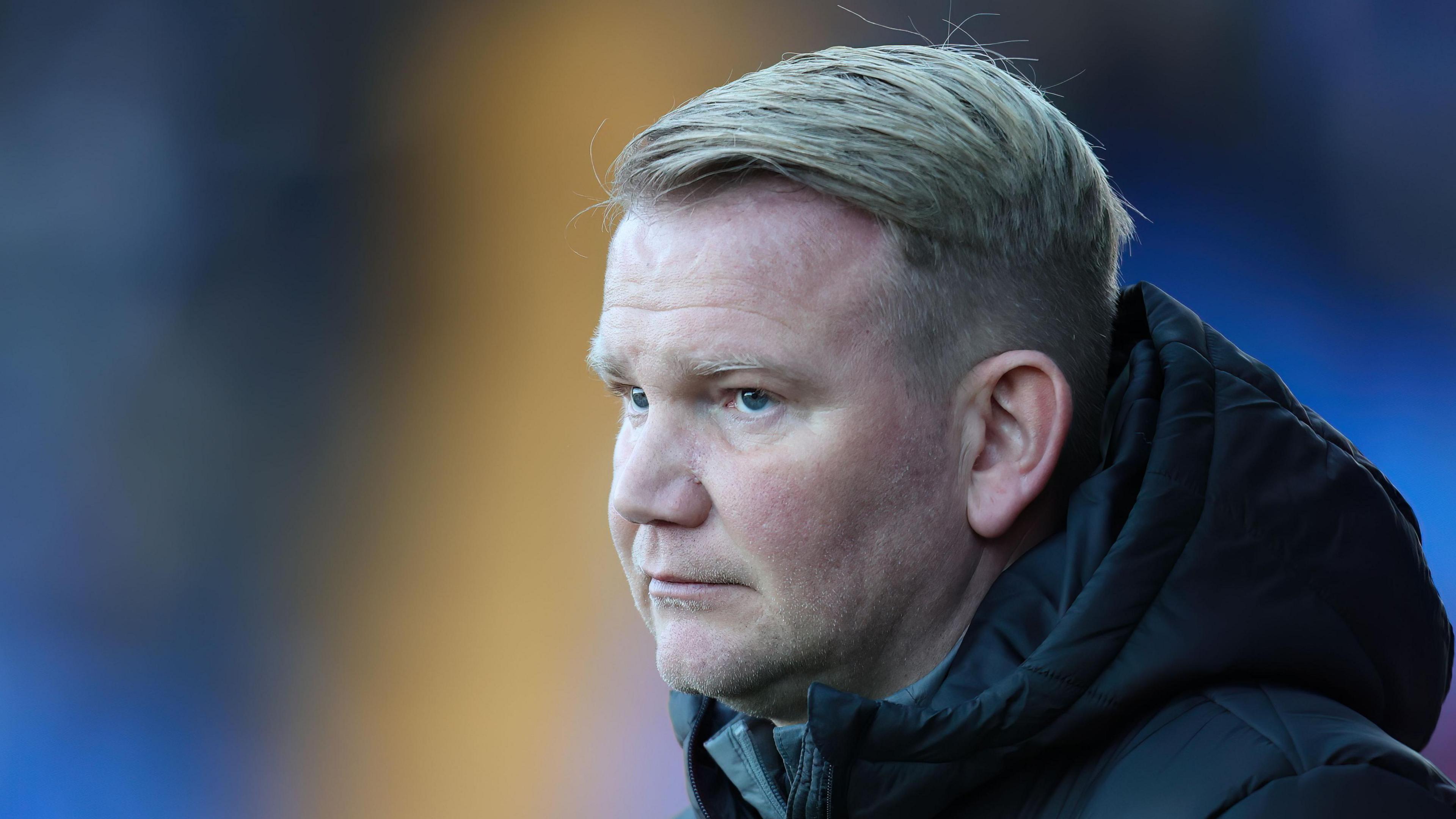 Pete Wild watching Fleetwood play, wearing a thick hooded jacket