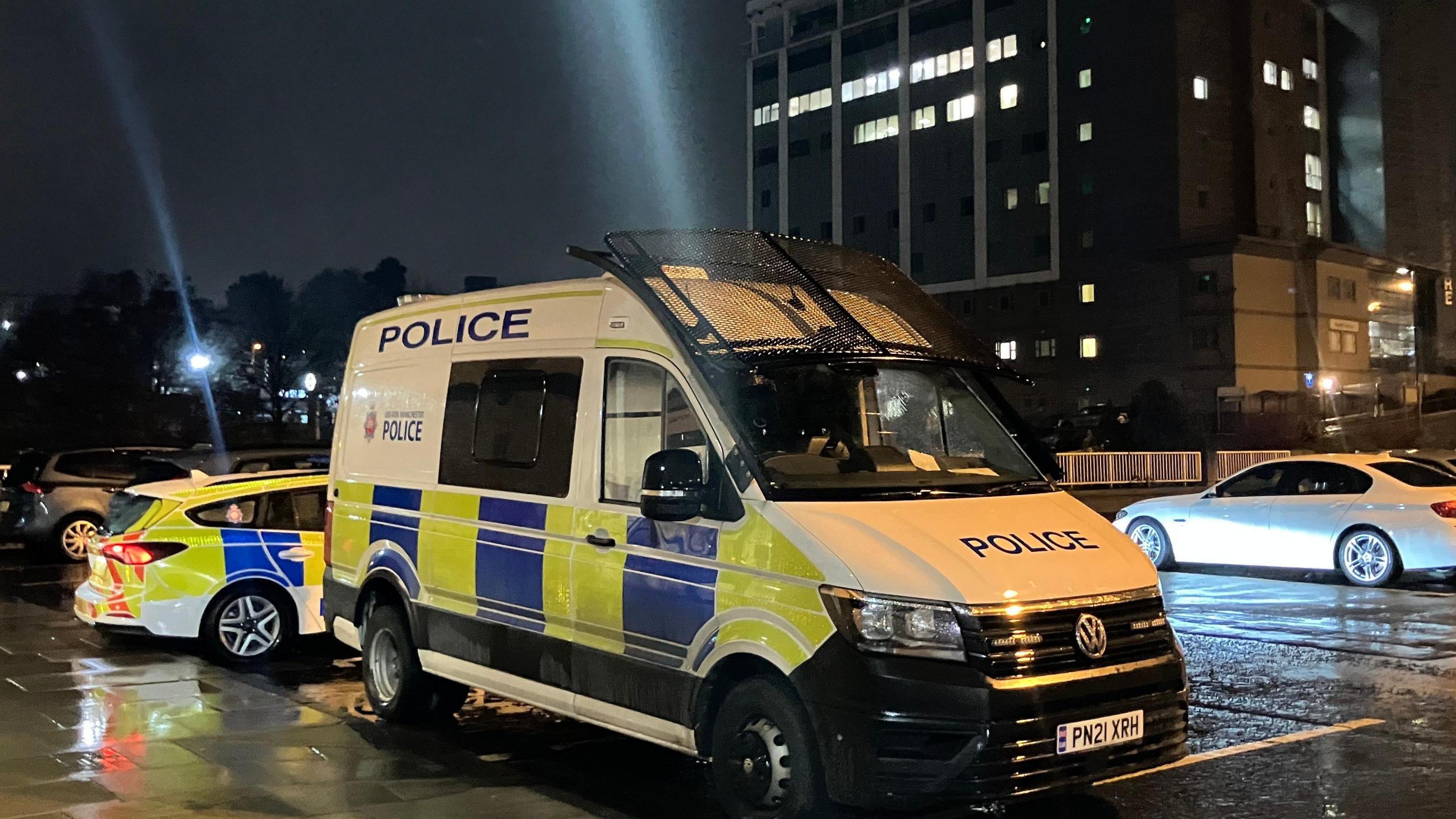 Police riot van outside Oldham Council at night on a rainy street