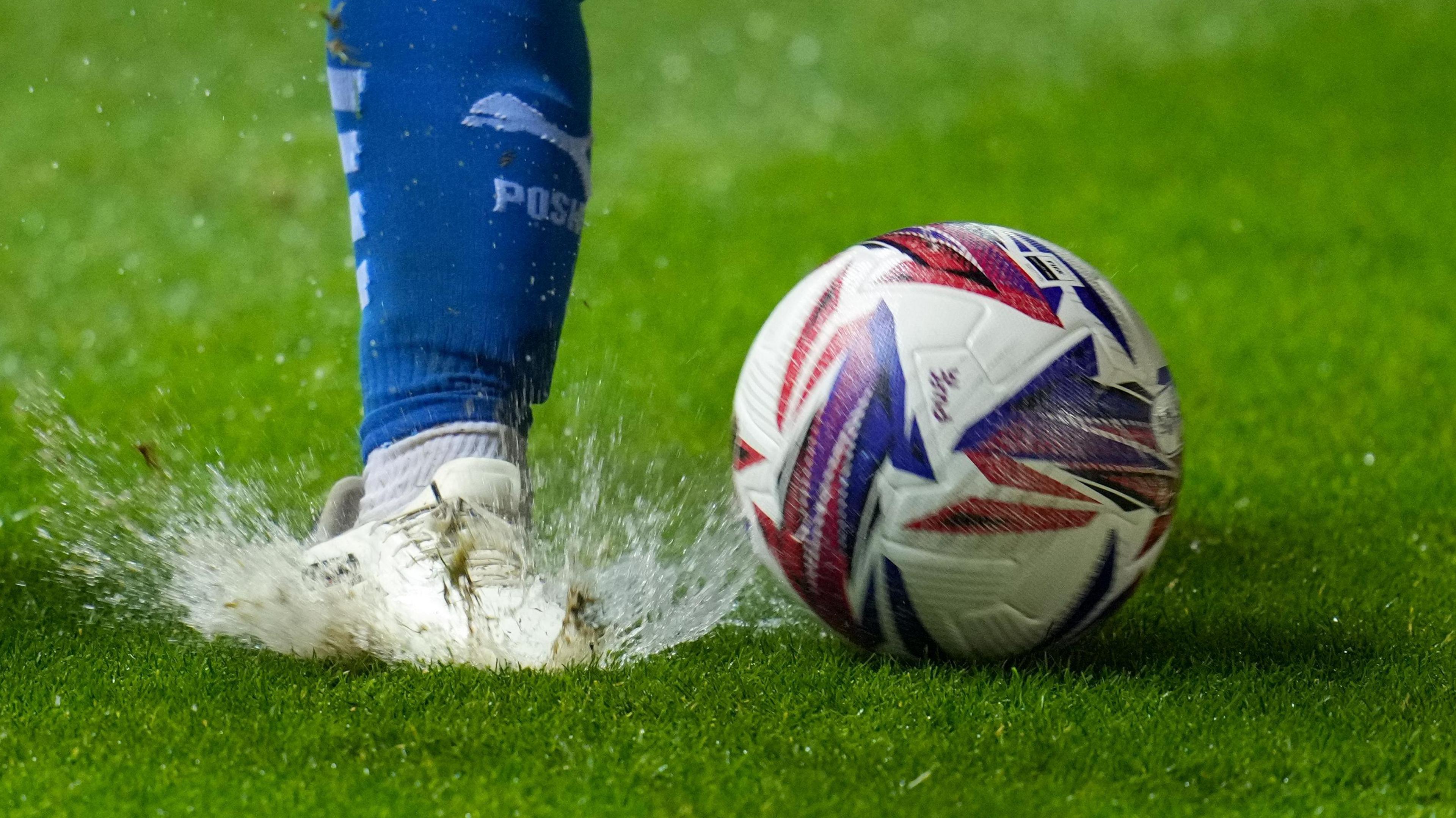 Surface water is visible as a Peterborough player plants his foot into the turf at London Road