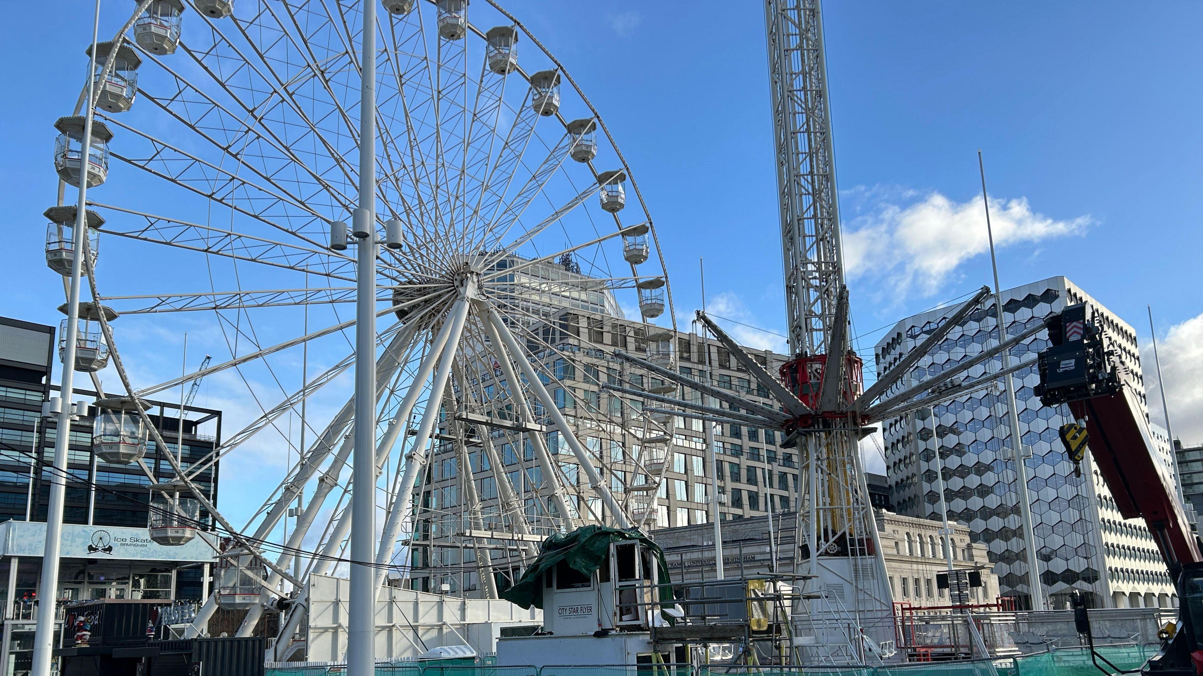 The of the City Star Flyer on Thursday. One man is in a hi-vis jacket. The ride can be seen cordoned off by a green fence with a big wheel in the background. 