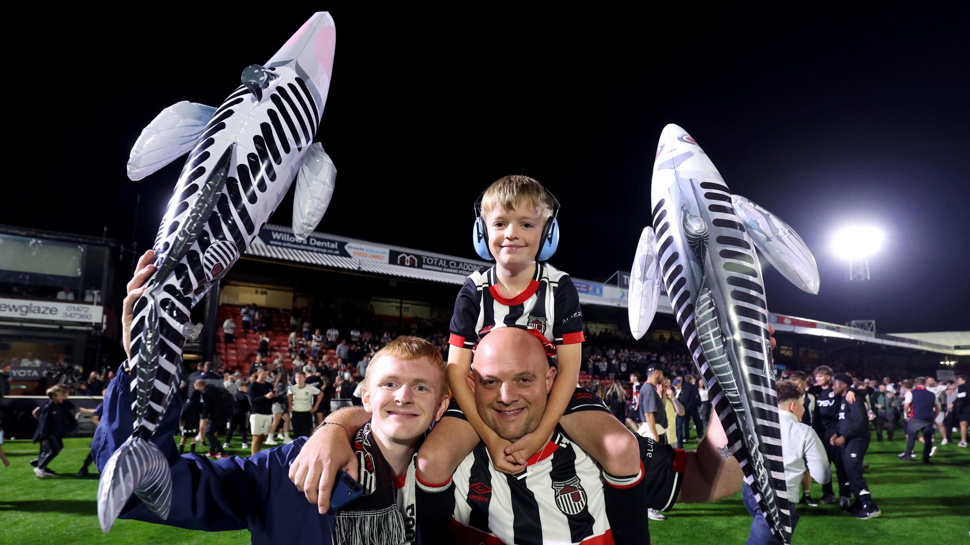 Fans celebrating after the game holding up inflatable Harry the Haddock mascots.
