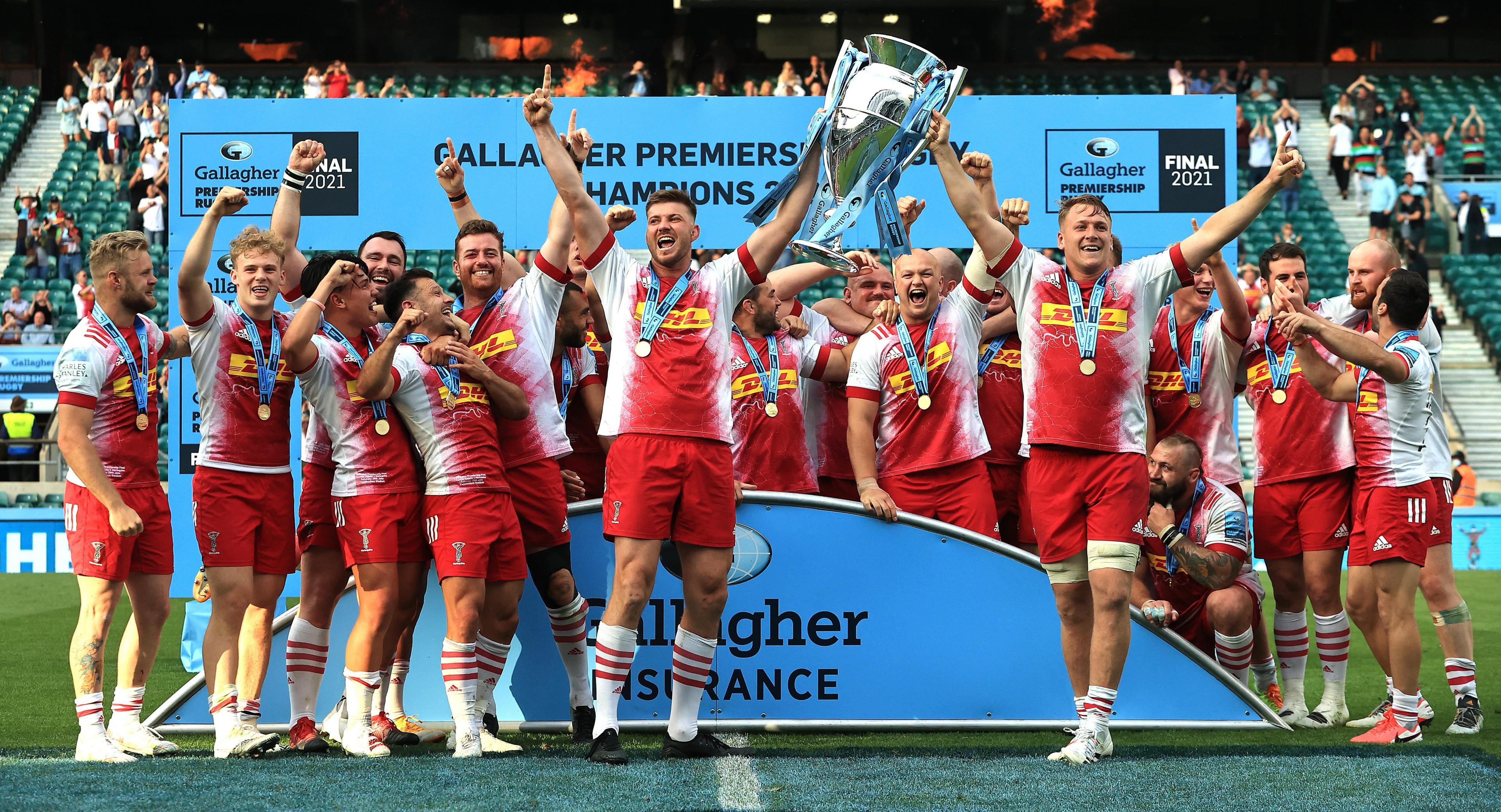 Harlequins players in their red and white kit, lifting the Premiership title in 2021.