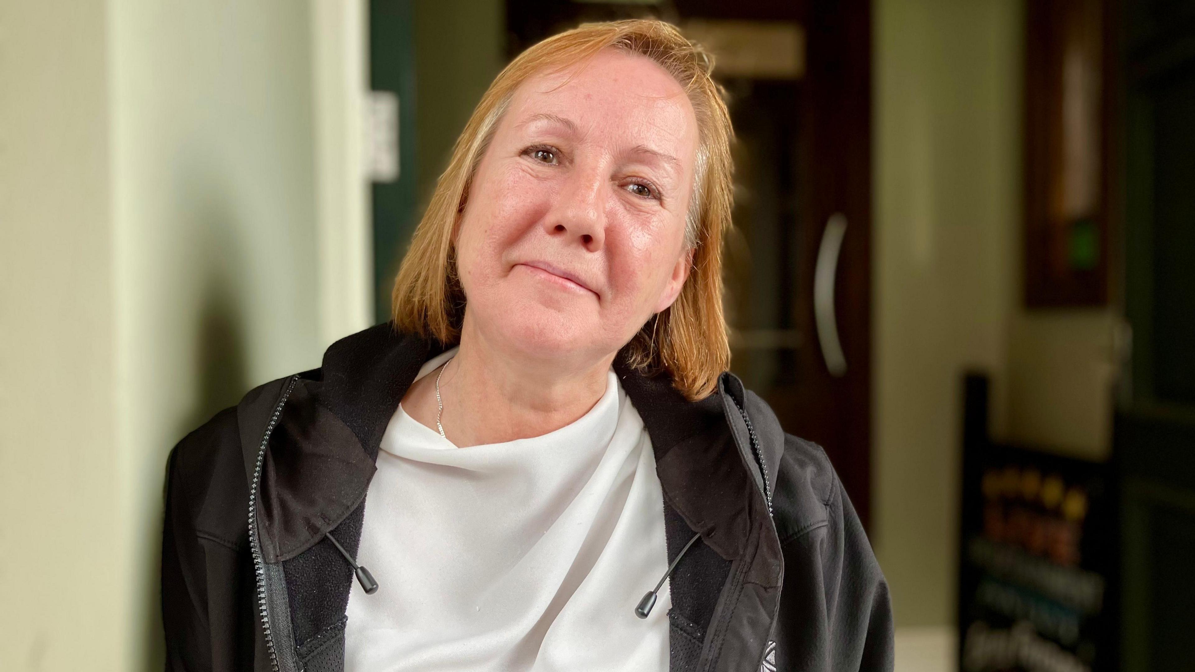 Restaurant supervisor Michelle Grierson, wearing a white top and black jacket, looking into the camera