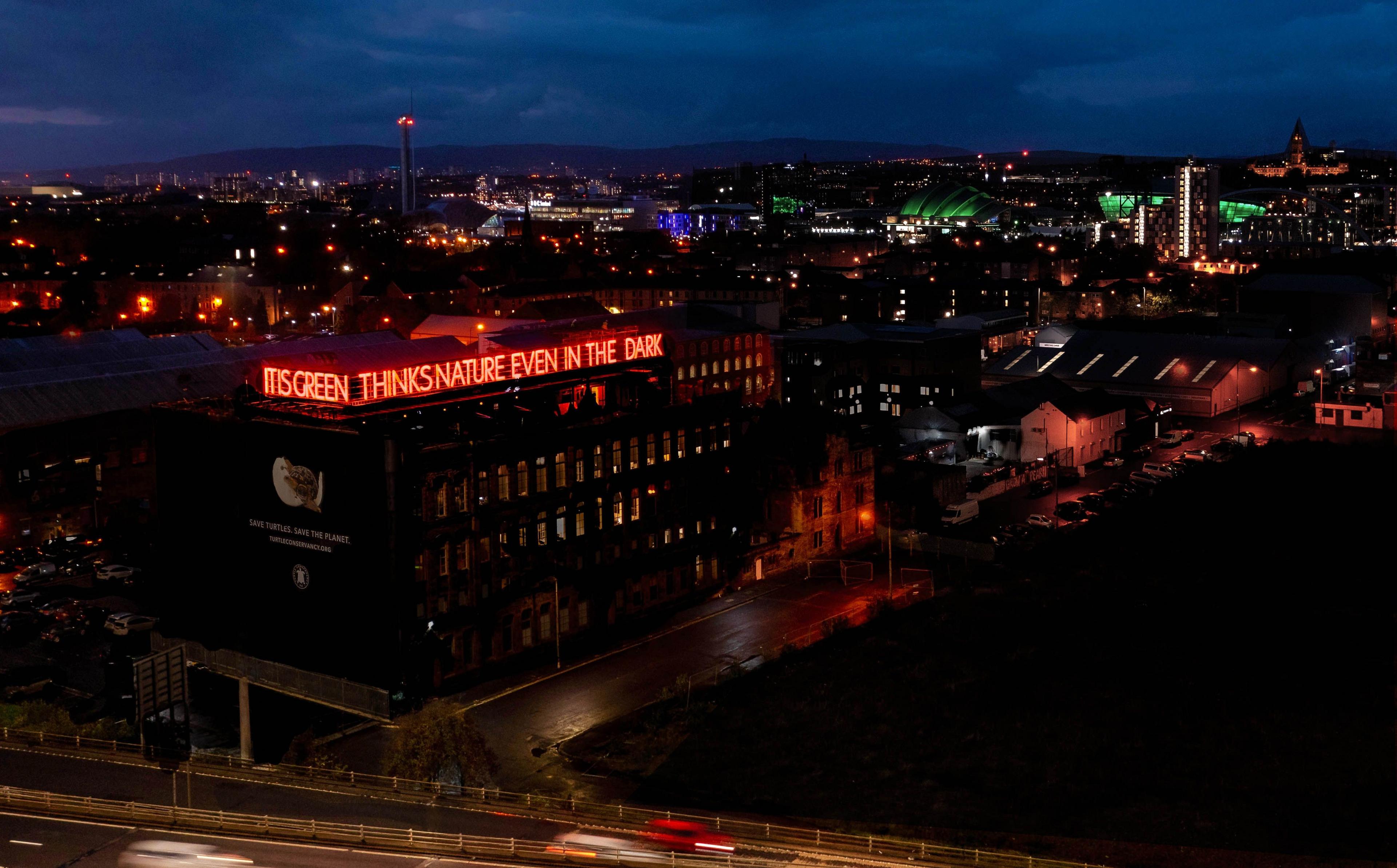 Drone picture of the sign with Glasgow’s skyline in the background. You can see the science centre tower, BBC Scotland, the Hydro and Glasgow University.