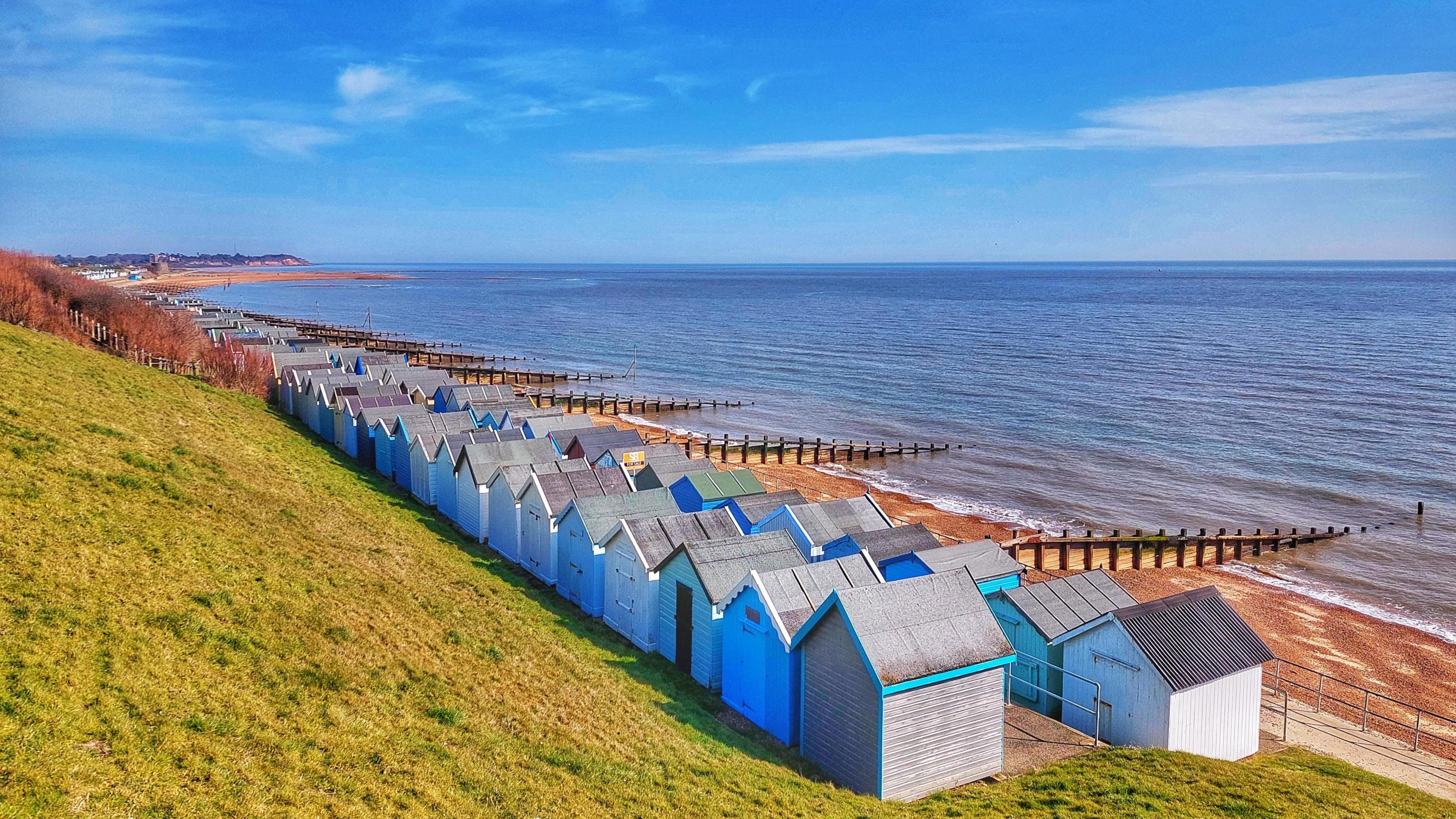 Beach huts next to the sea with blue skies in Walton, Suffolk