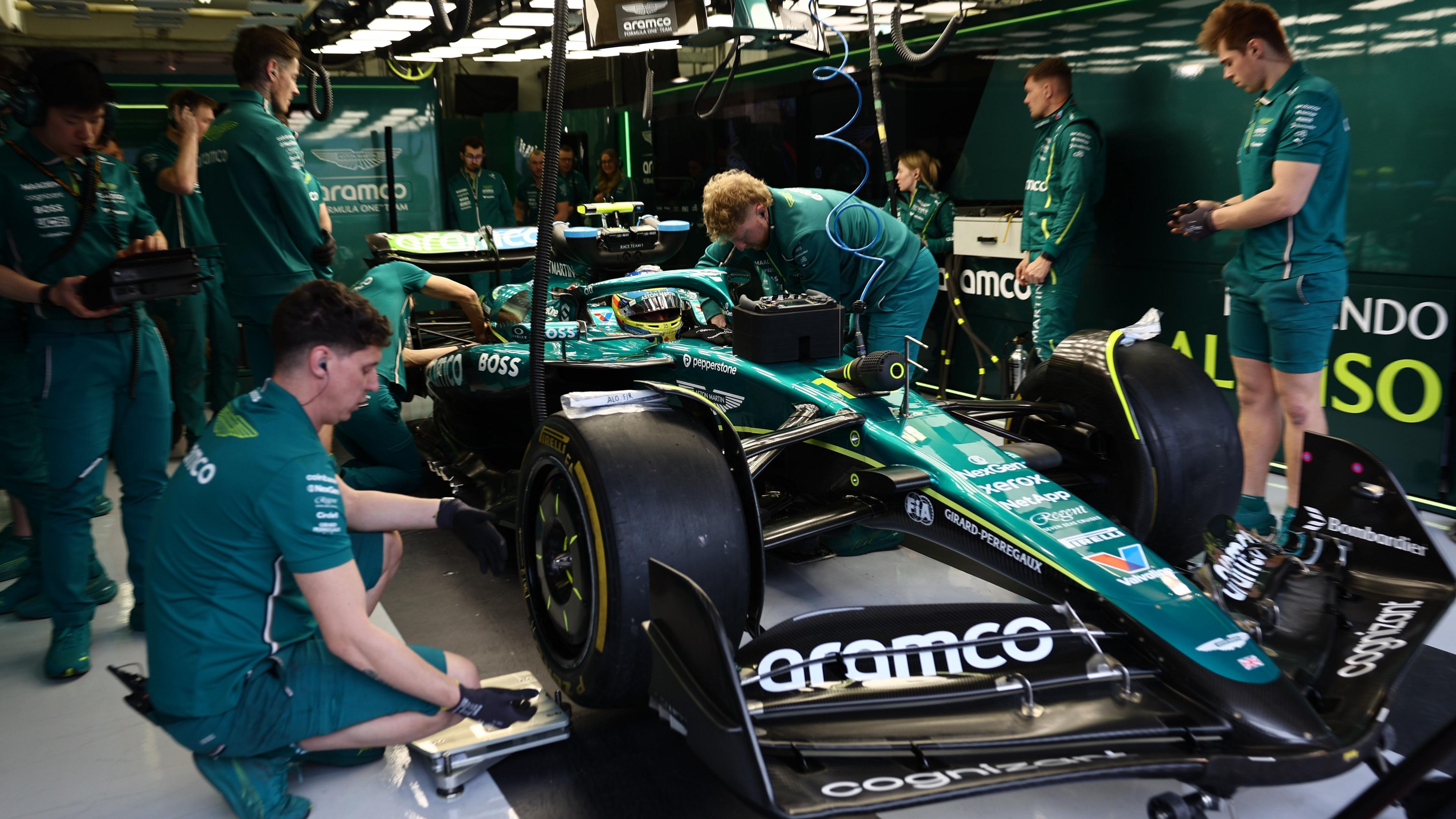 Crew were deep green working around a F1 car in the pits during testing in the Bahrain Grand Prix