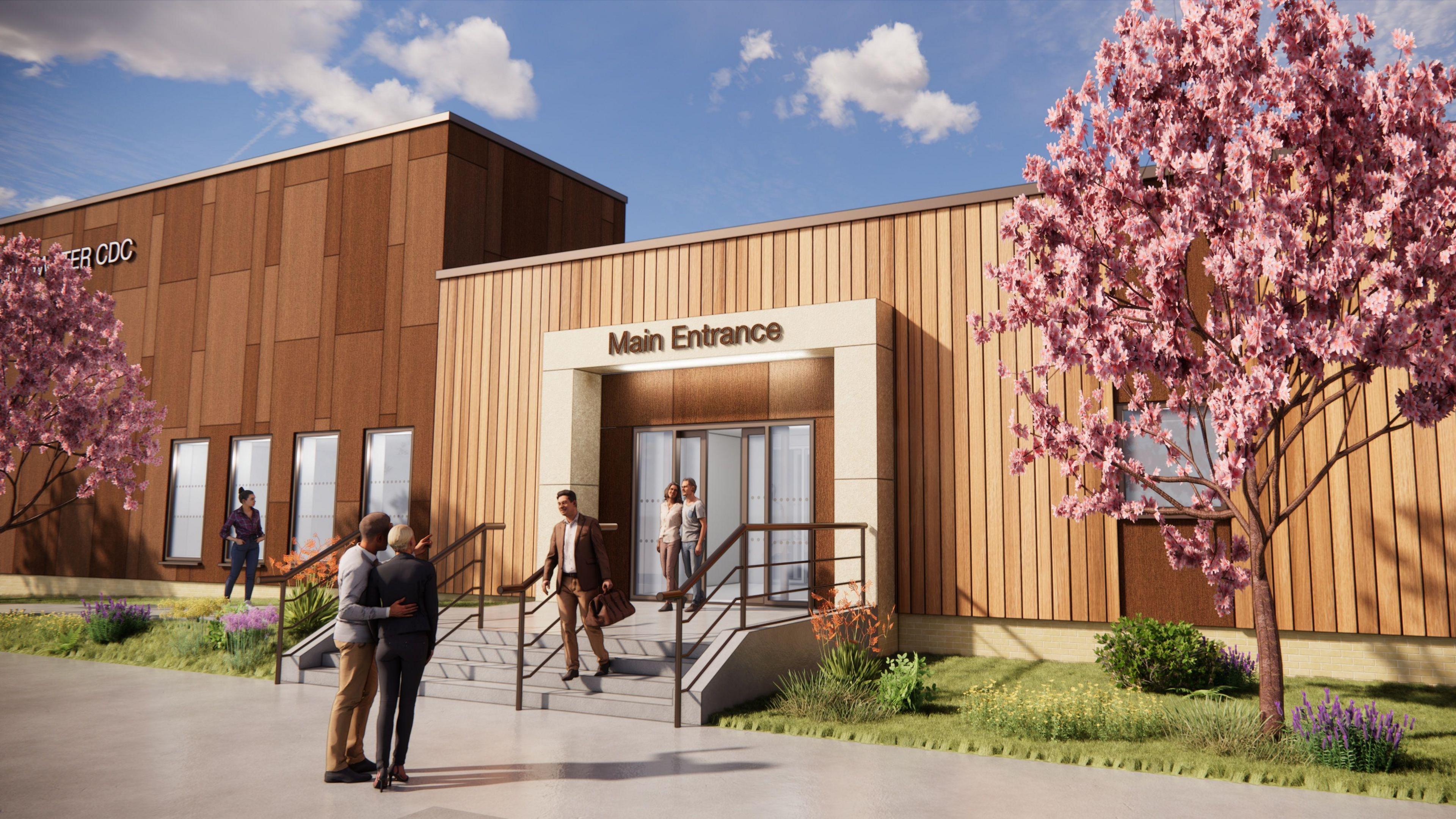 A computer generated image of what the new diagnostic centre will look like. It is a large rectangular building clad in wooden planks. There are a set of stone steps leading up to an entrance with automatic doors. There are two cherry blossom trees growing on either side of the entrance on a patch of grass and flowers.