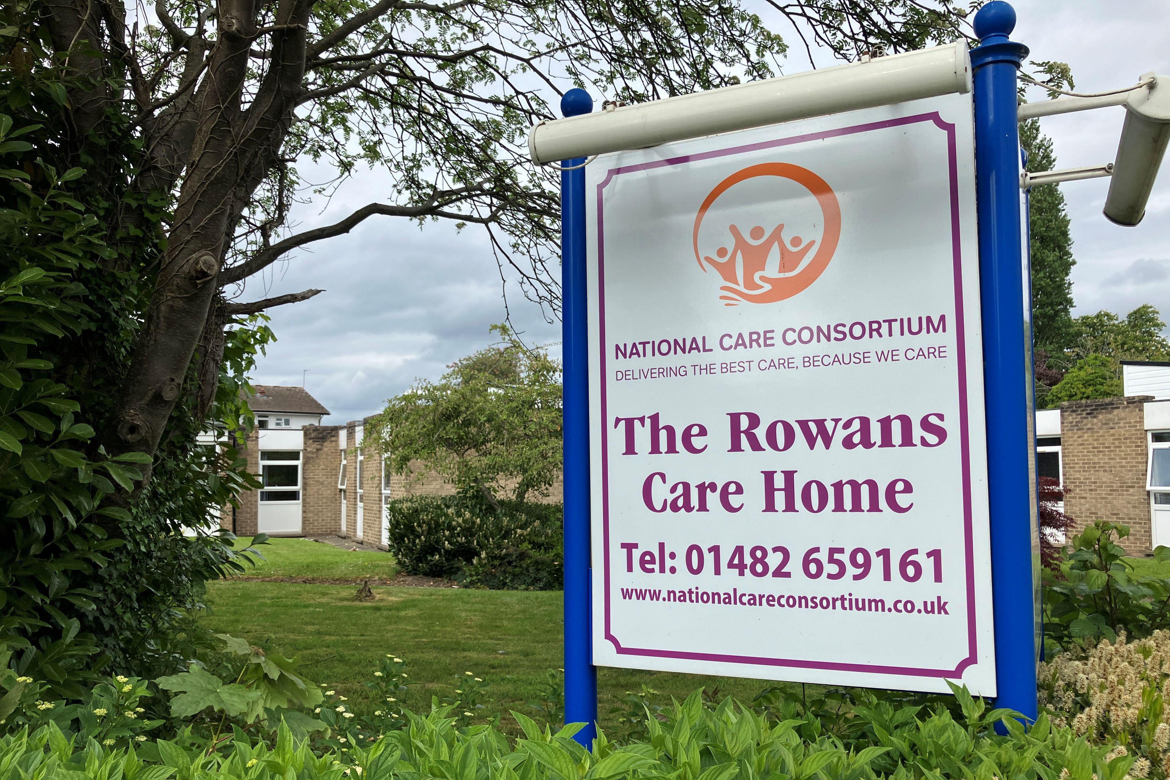 Brick one-storey building with windows and surrounded by trees. There is a sign in front which reads National Care Consortium, delivering the best care because we care, The Rowans Care Home. Tel: 01482 659161. www.nationalcareconsortium.co.uk.