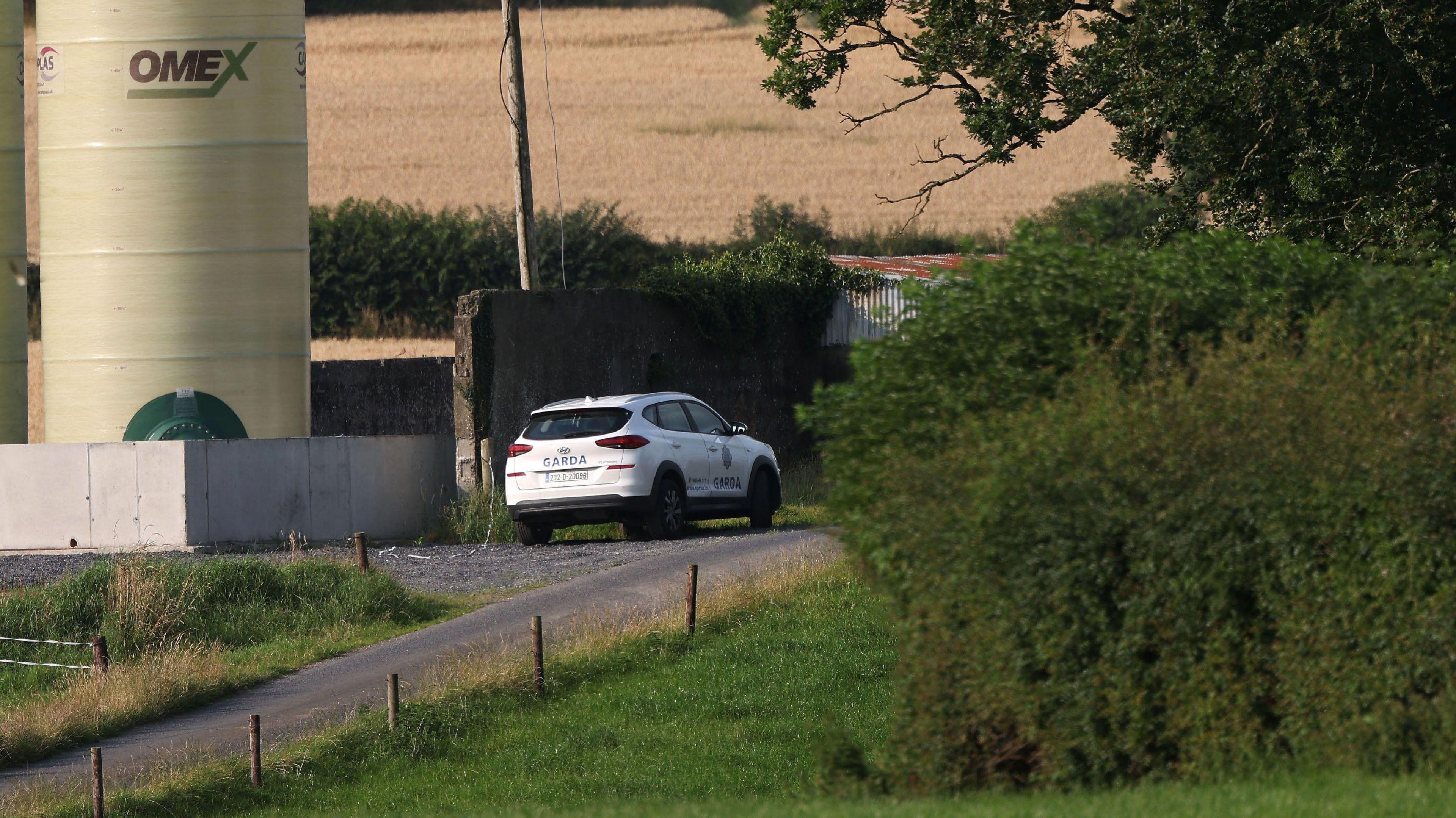 A Garda car in the centre of the photo, parked on a country road