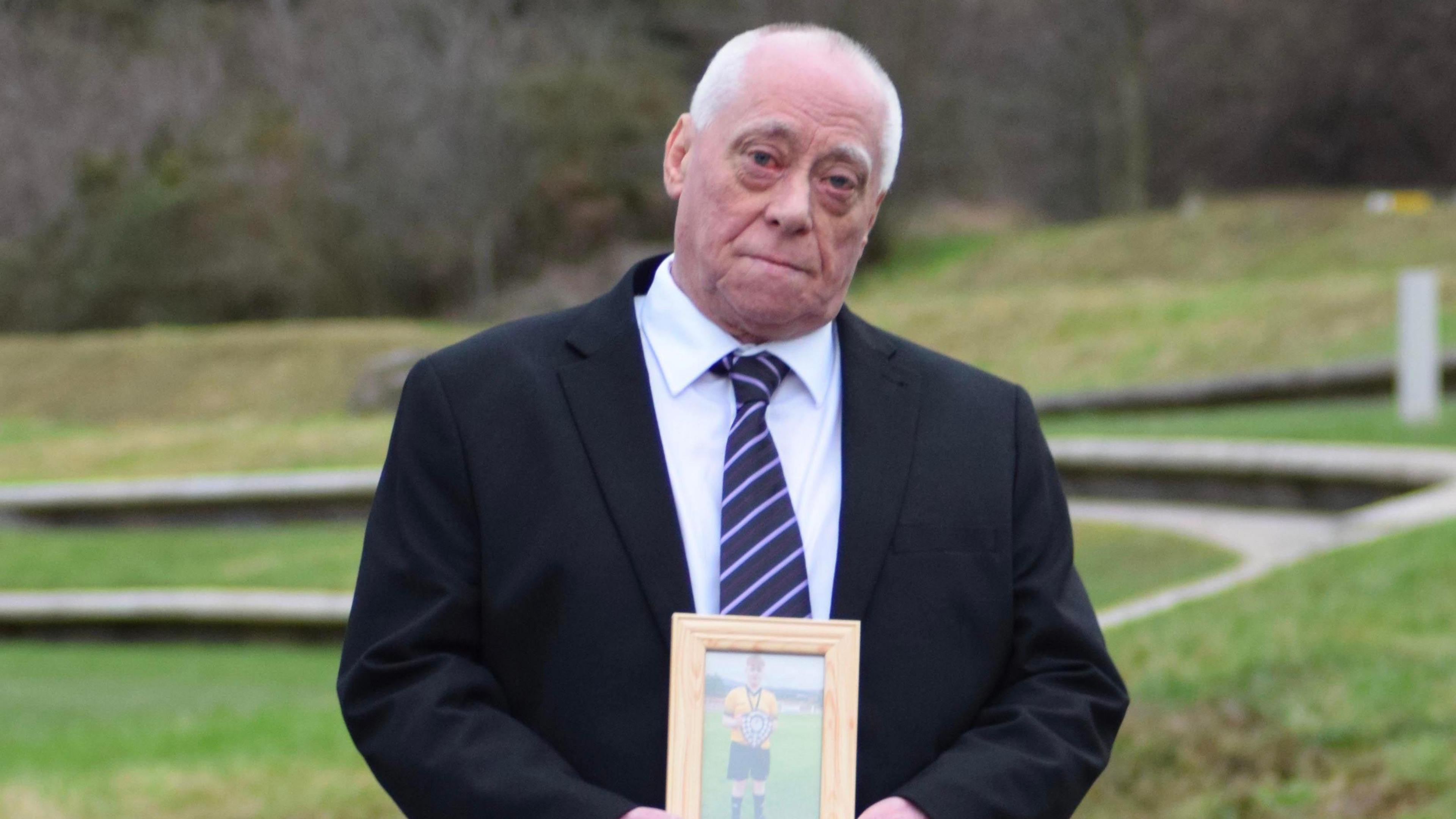 Alan Knox a' cumail dealbh de a mhac a chaill a bheatha ann an tubaist rathaid